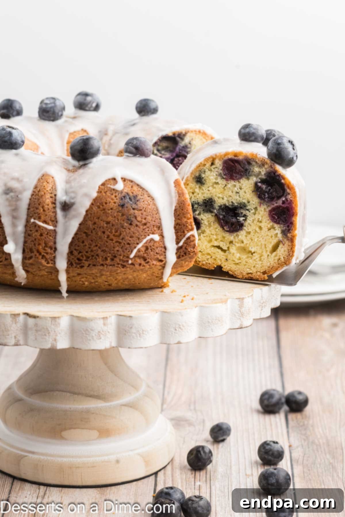Sapphire Swirl Cake 9 A Blueberry Bundt Cake being elegantly sliced, revealing its tender, berry-filled interior.