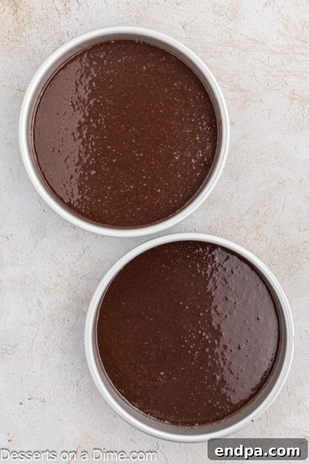 Ultimate Dark Chocolate Decadence 6 The dark chocolate cake batter is evenly poured into two prepared cake pans, ready for baking.