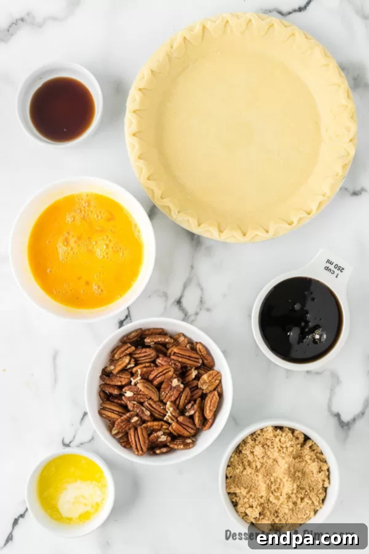 A collection of ingredients laid out: eggs, corn syrup, brown sugar, butter, vanilla extract, and pecan halves, ready for baking.