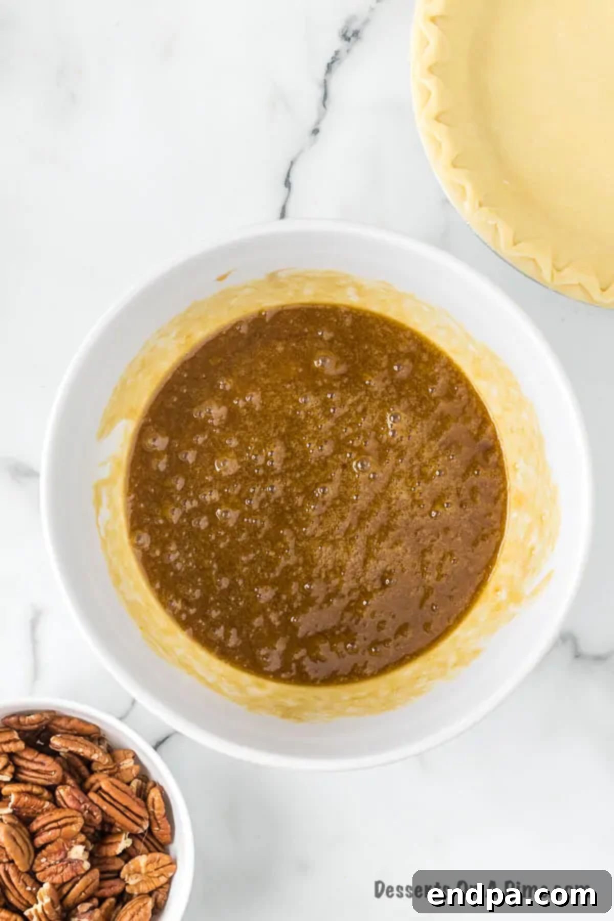 A large bowl containing beaten eggs, corn syrup, and brown sugar, perfectly combined for the pecan pie filling.