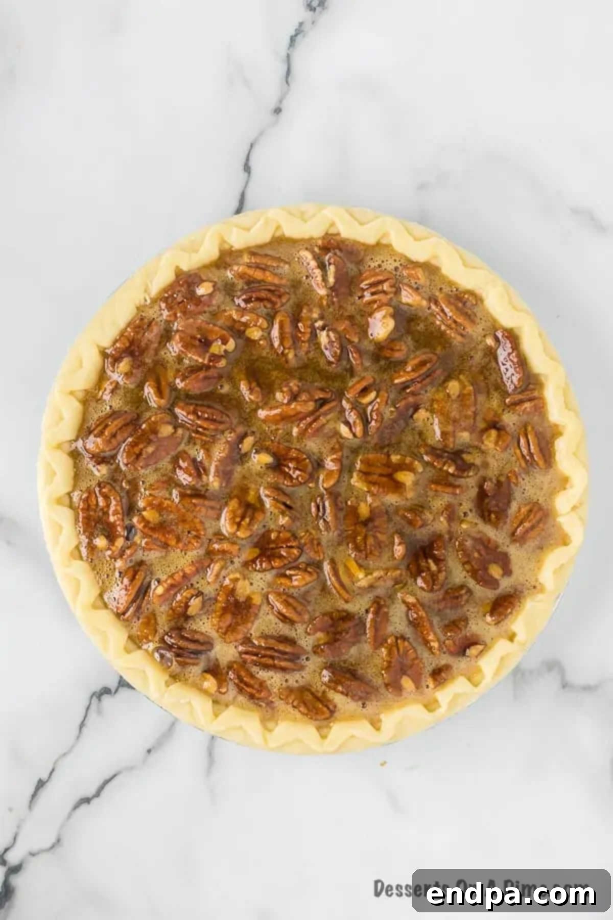 The pecan pie filling being carefully poured into an unbaked pie crust, set in a pie pan.
