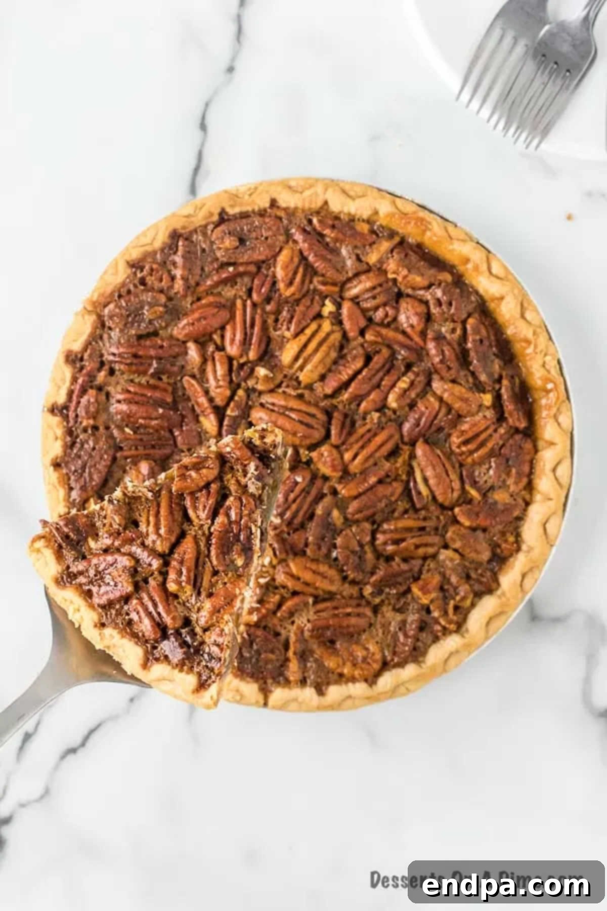 A whole pecan pie in a pie pan, with one slice being lifted out on a spatula, ready to serve.