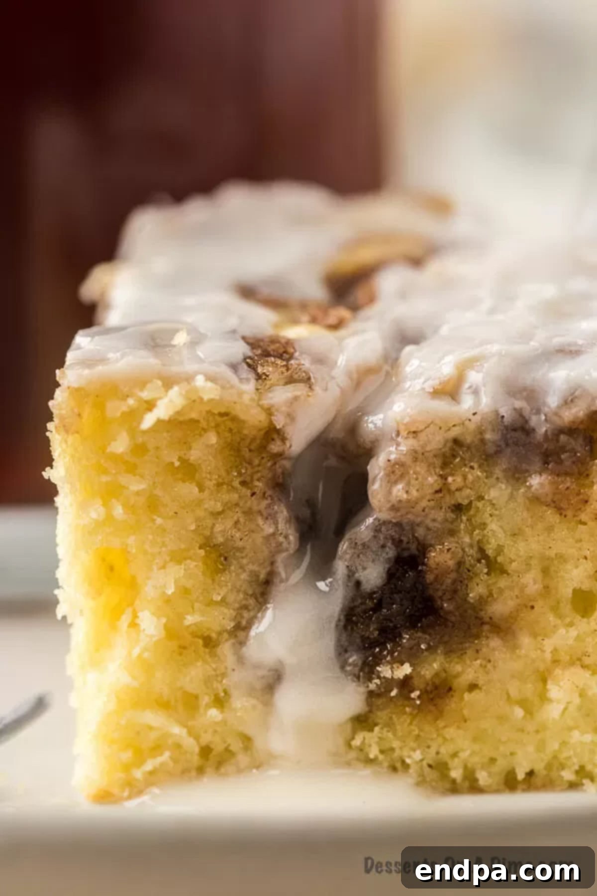 Indulgent Cinnamon Roll Cake Delight 11 Close up picture of a piece of the cinnamon roll cake on a white plate