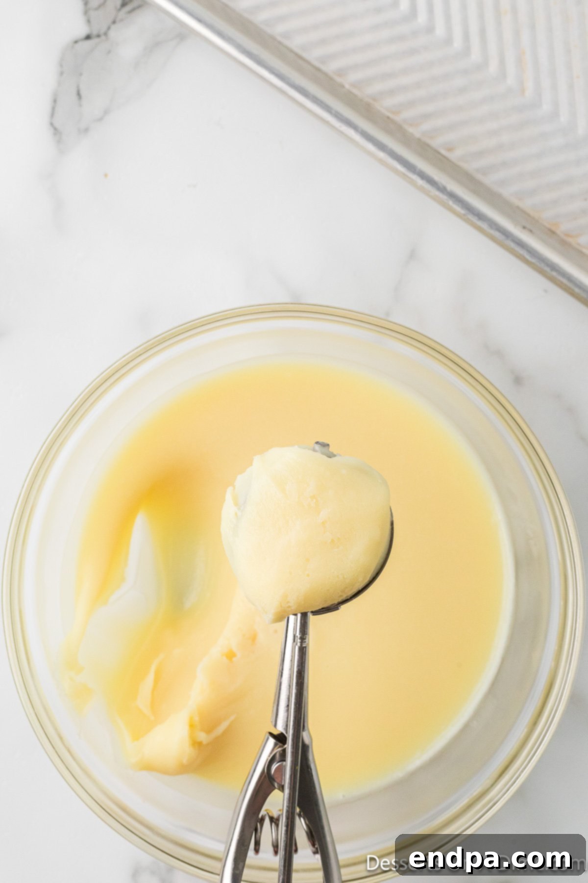 Neatly rolled 1-inch white chocolate truffle balls arranged on parchment paper on a baking sheet.