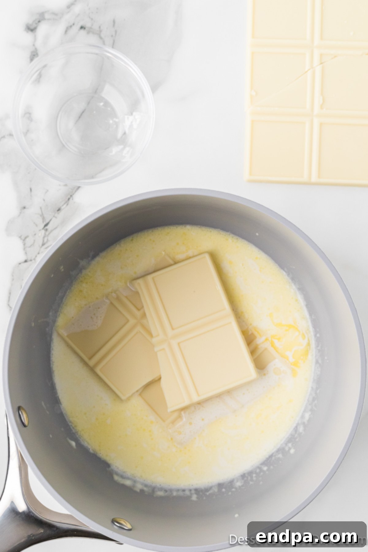 The white chocolate, cream, and butter mixture being stirred until smooth and fully melted, forming a creamy ganache.