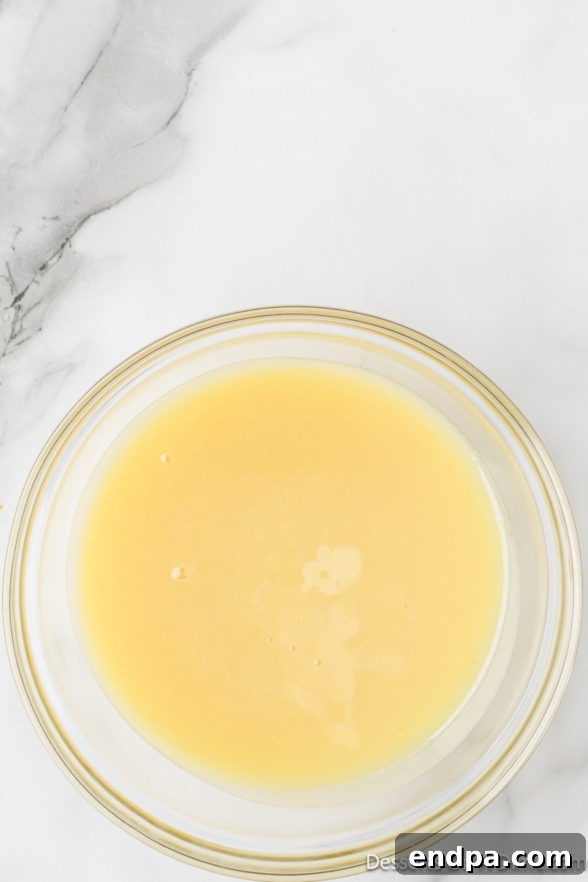 The chilled and firmed white chocolate ganache in a glass bowl, ready to be scooped and shaped.