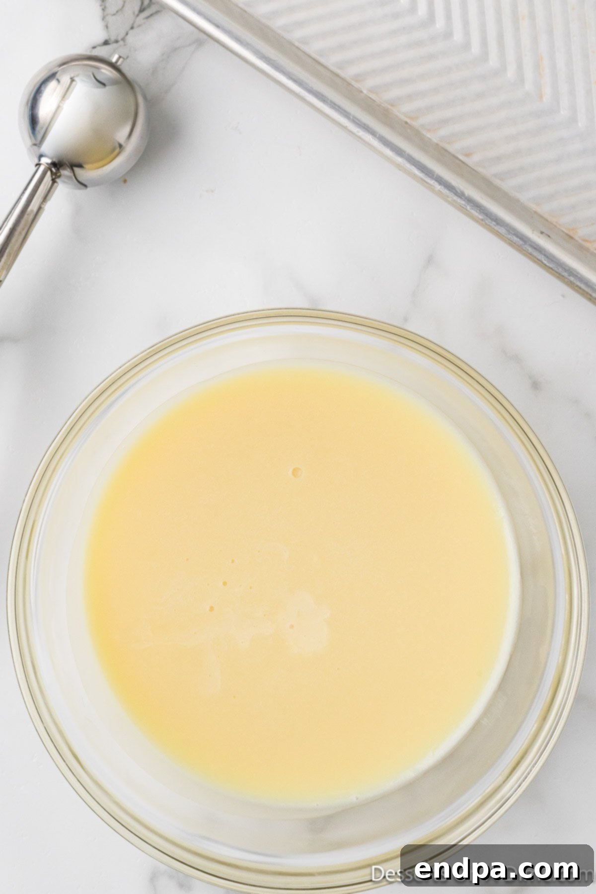 Portioning the chilled white chocolate ganache with a cookie scoop onto parchment paper.