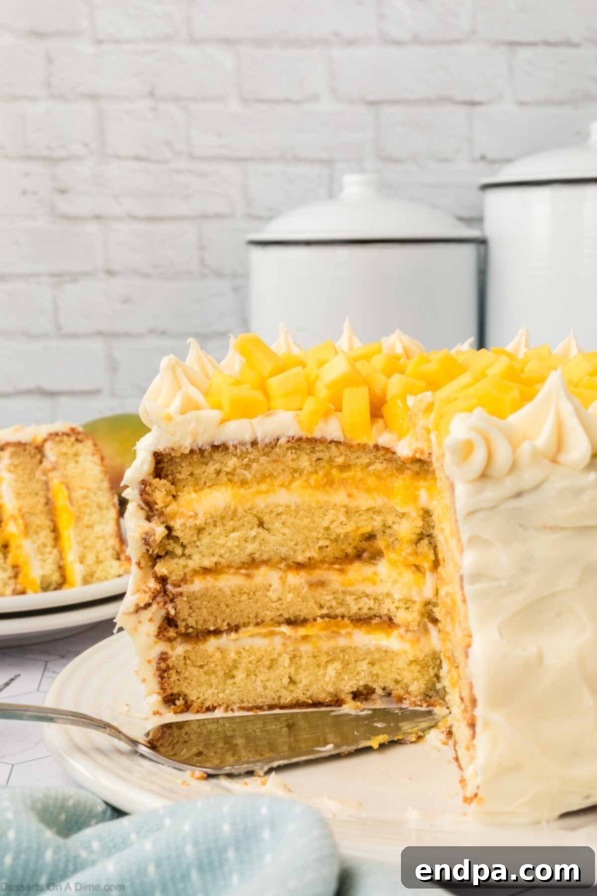 A beautiful slice of Mango Cake revealing its soft vanilla layers, vibrant mango puree, and creamy frosting.