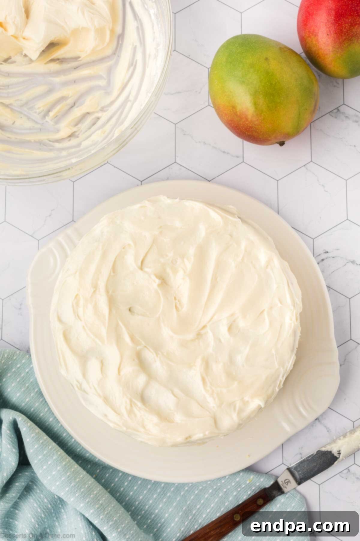 The sides and top of the layered mango cake fully frosted with smooth cream cheese frosting, ready for final decoration.
