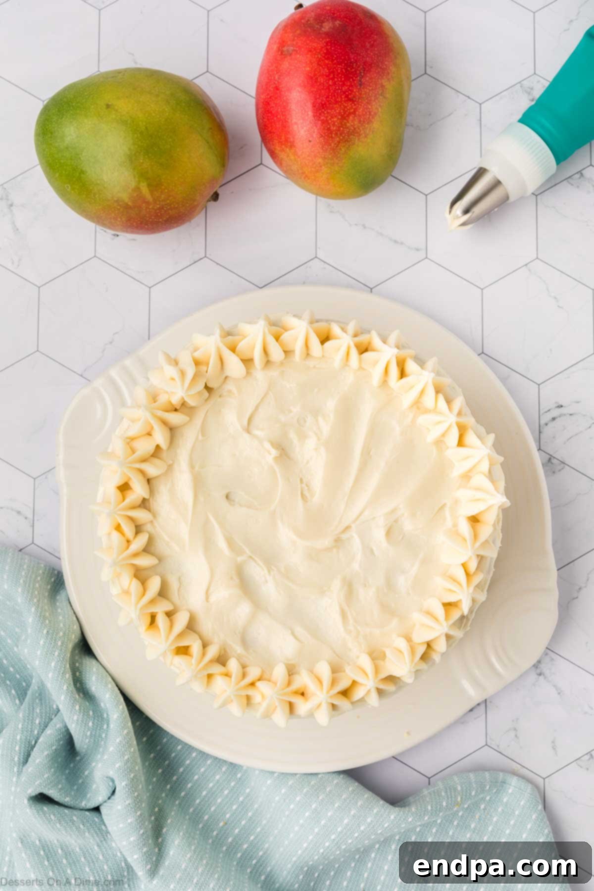 Cream cheese frosting piped with a star tip around the outer top border of the mango cake for decoration.