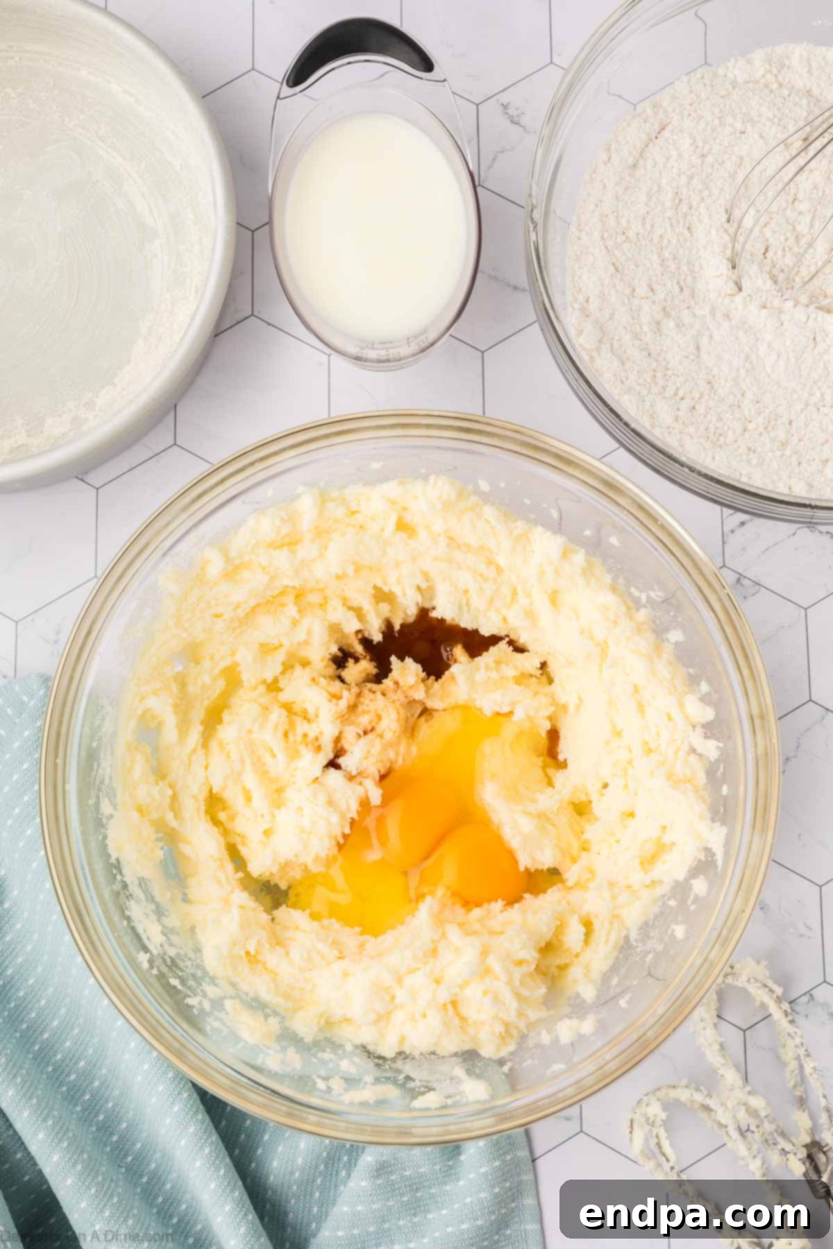 Room temperature eggs and pure vanilla extract added to the creamed butter and sugar mixture, ready to be combined.