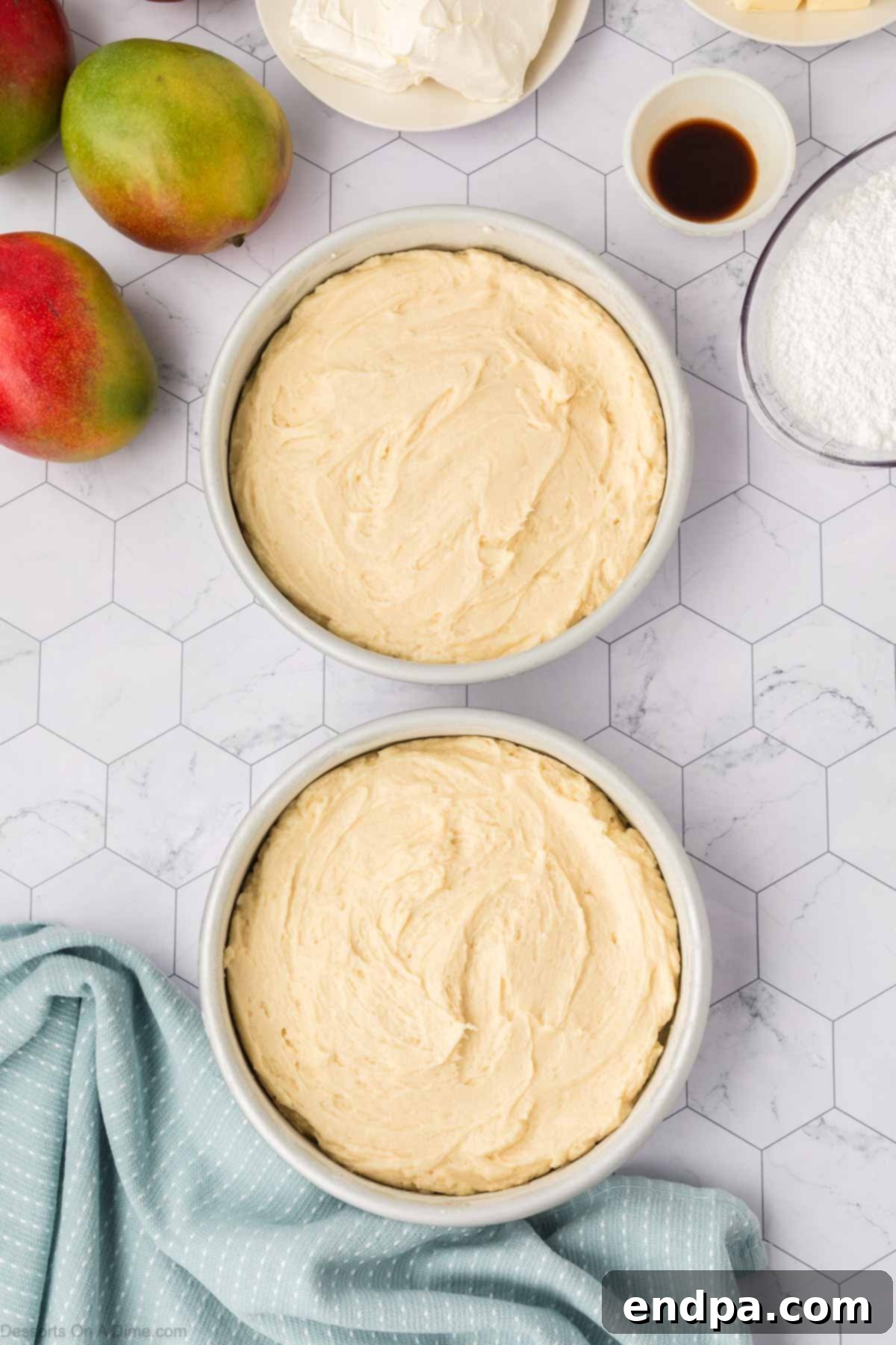 Thick cake batter spread evenly into two prepared round cake pans, ready for the oven.