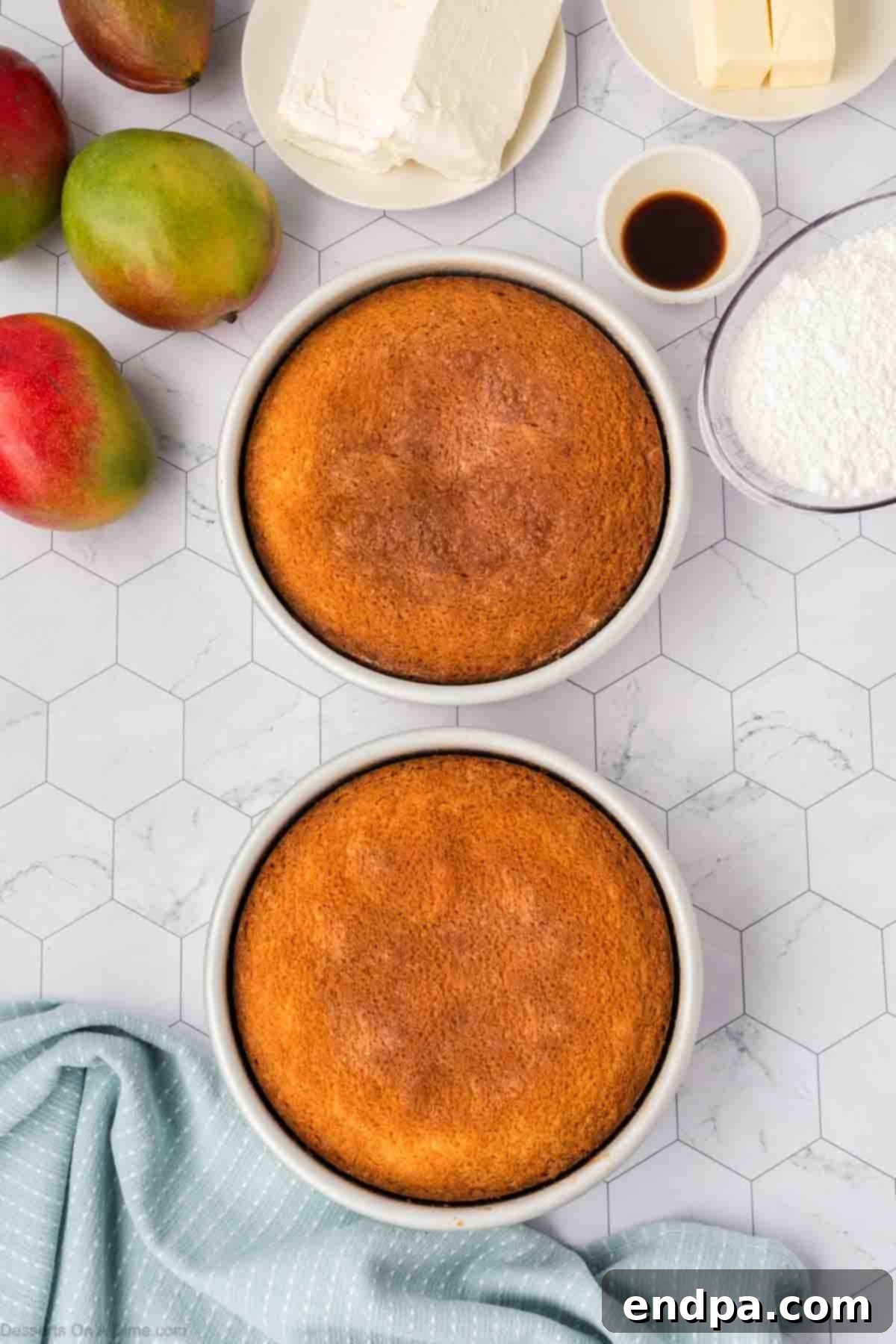 Two baked cake layers cooling in their pans after being removed from the oven.