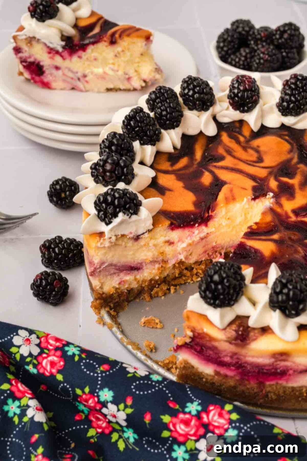 A slice of Blackberry Cheesecake being carefully lifted from the main cake, showcasing its creamy texture and vibrant blackberry swirls.
