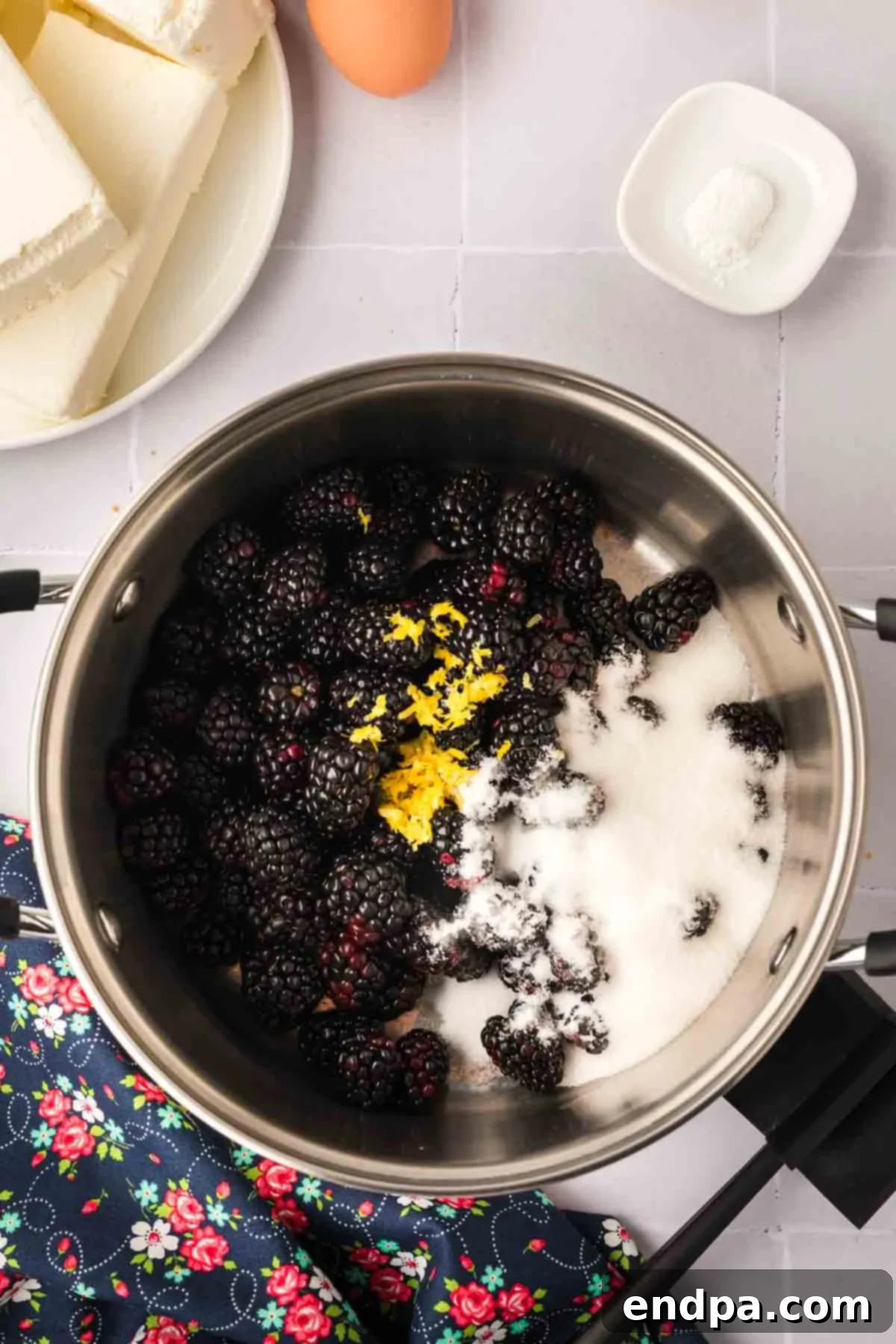 Fresh blackberries, sugar, lemon juice, and lemon zest combined in a saucepan on the stovetop, beginning to cook for the puree.