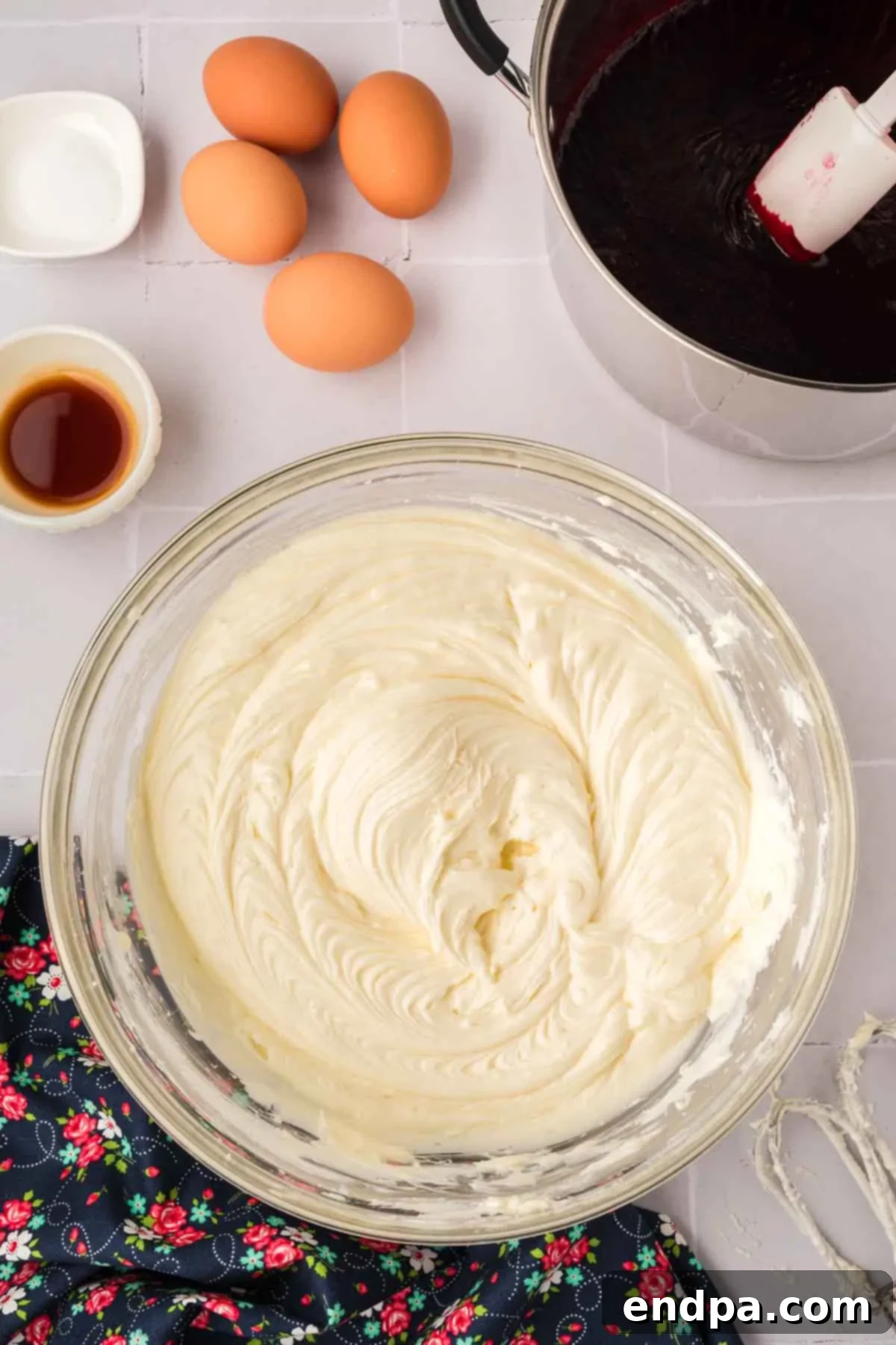 Cream cheese being beaten in a stand mixer with a paddle attachment until it is light, fluffy, and smooth.