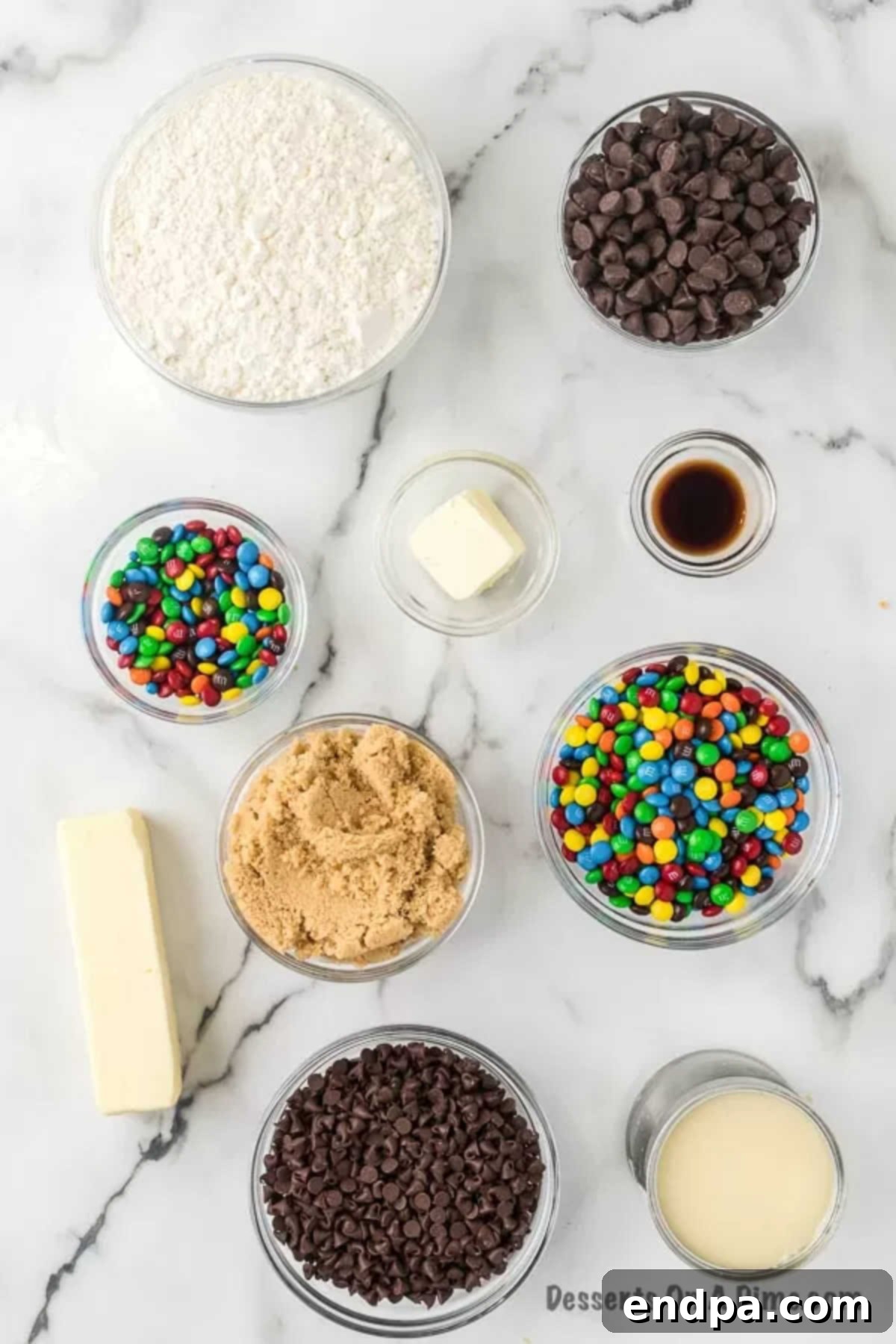A selection of ingredients for no-bake cookie dough bars including butter, brown sugar, vanilla extract, sweetened condensed milk, chocolate chips, and M&M's.