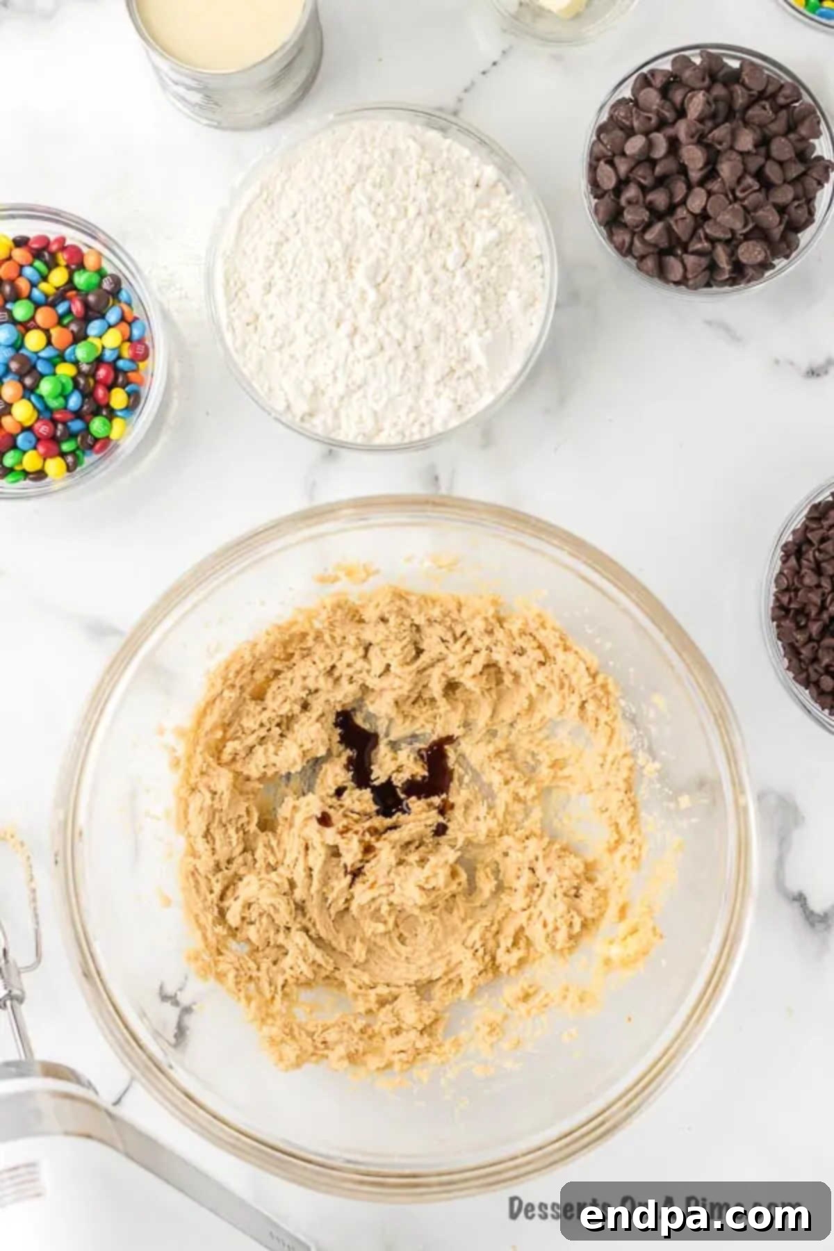 Vanilla extract being poured into the creamed butter and sugar mixture.