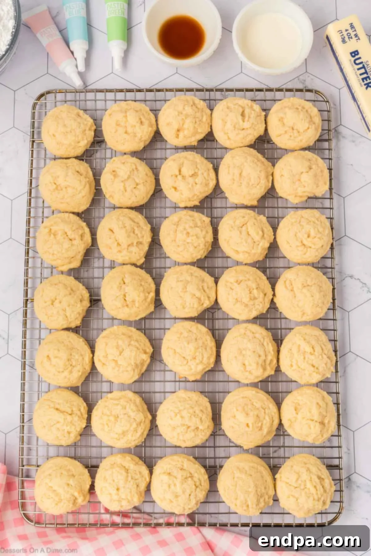 Cloud-Soft Sour Cream Cookies 11 Freshly baked Sour Cream Sugar Cookies cooling on a wire rack after being removed from the baking sheet.