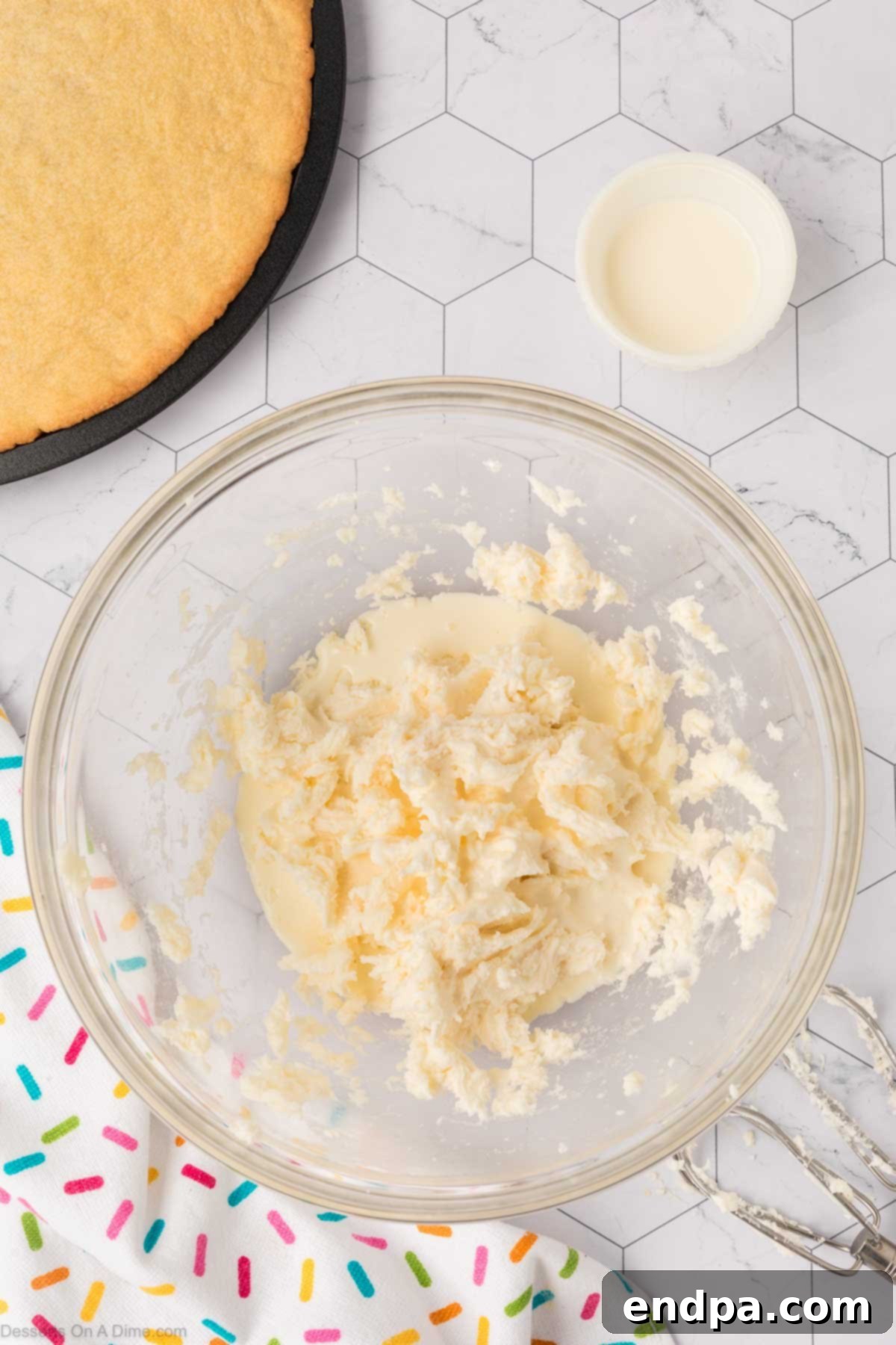Vanilla extract being poured into the butter and powdered sugar mixture, ready to be incorporated into the buttercream.