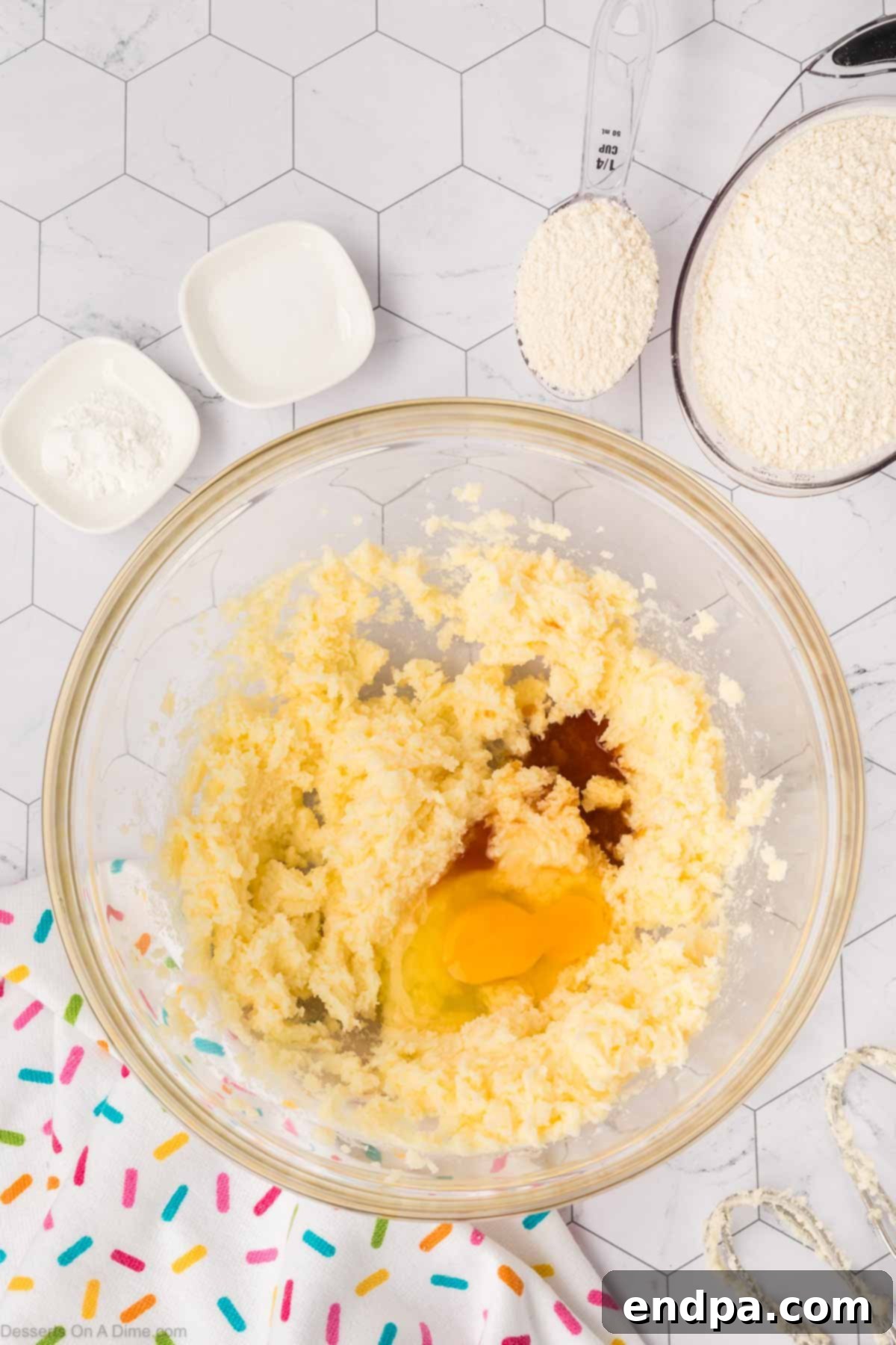 A mixing bowl with the creamed butter and sugar, now with an egg and vanilla extract added, ready to be gently combined.