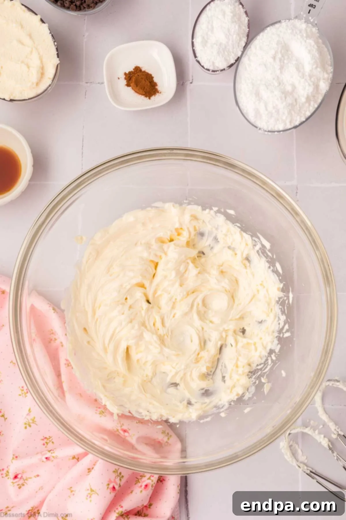 Softened cream cheese being beaten until light and fluffy in a mixing bowl with an electric mixer.