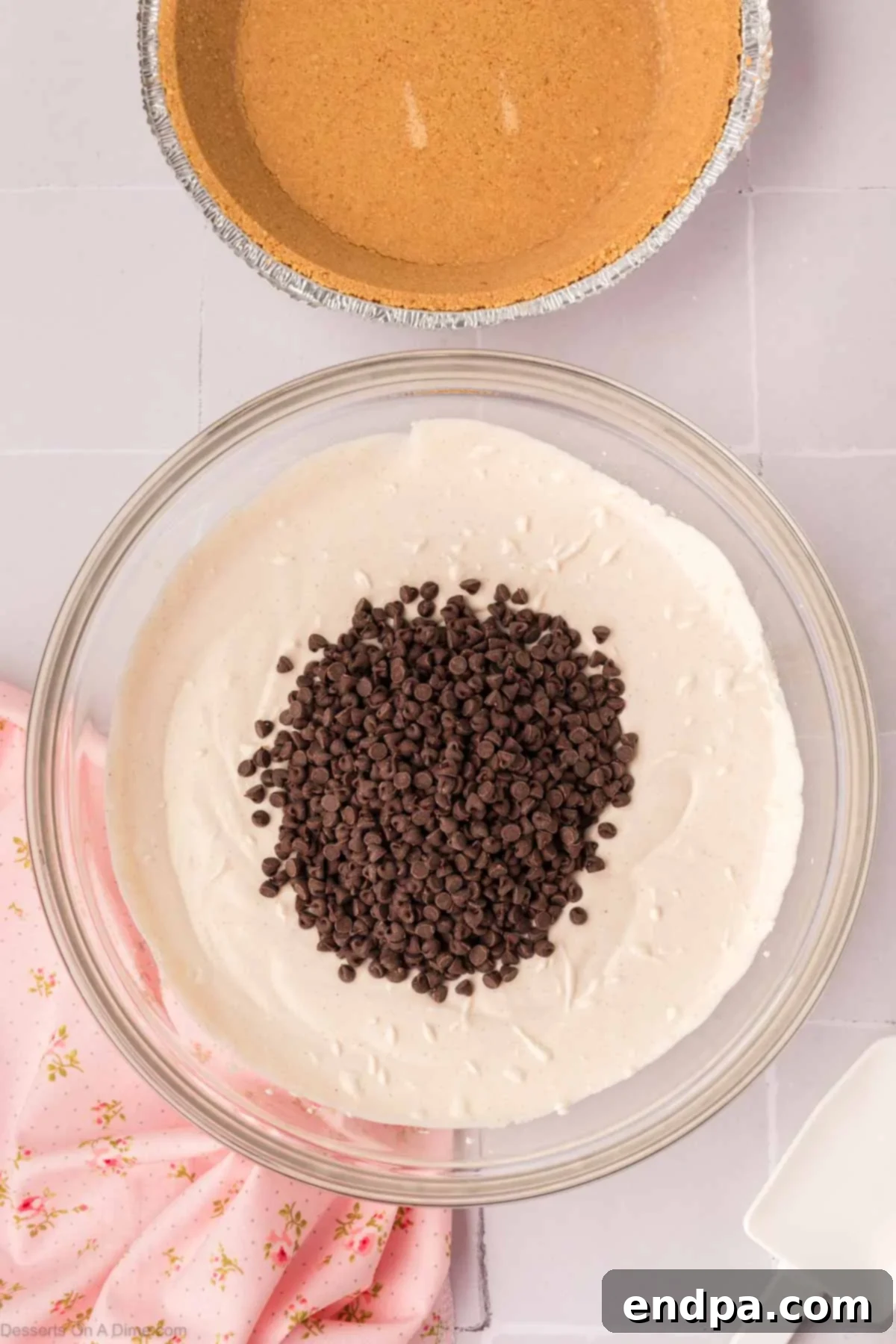 Mini chocolate chips being gently folded into the cannoli pie filling mixture by hand.