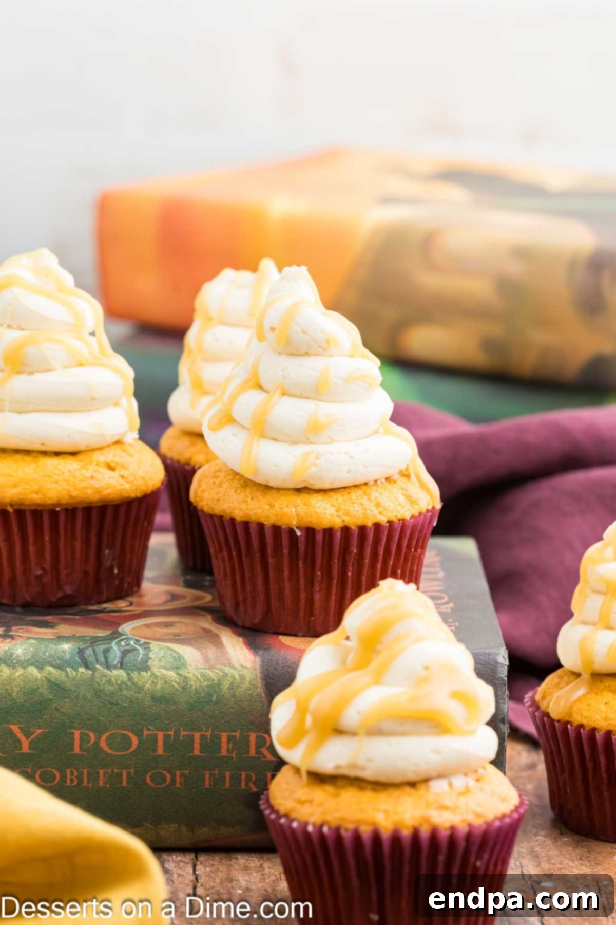 Harry Potter Butterbeer Cupcakes beautifully arranged on an antique book, showcasing their rich butterscotch frosting and enchanting appeal.