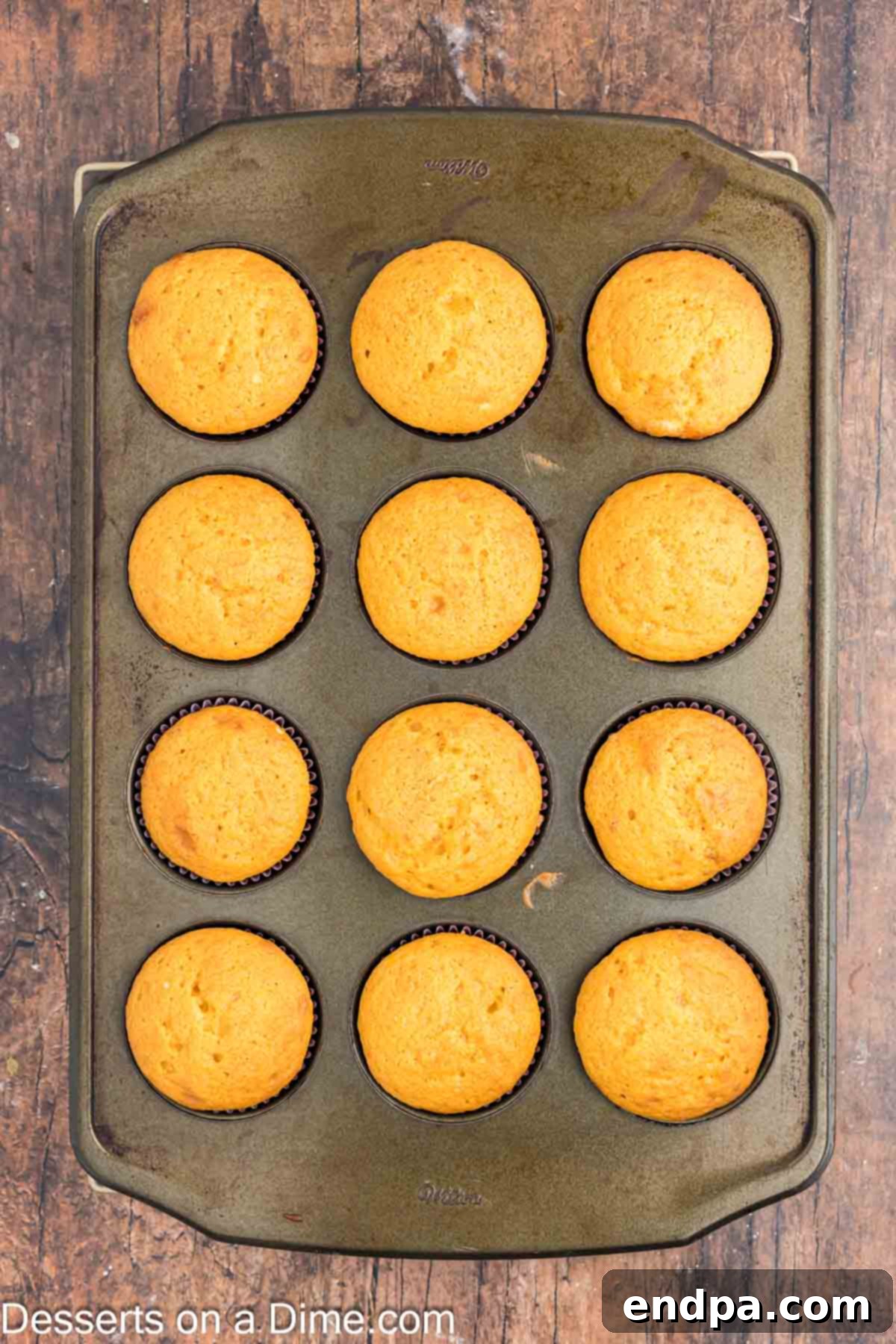 Freshly baked cupcakes cooling on a wire rack after being removed from the pan.