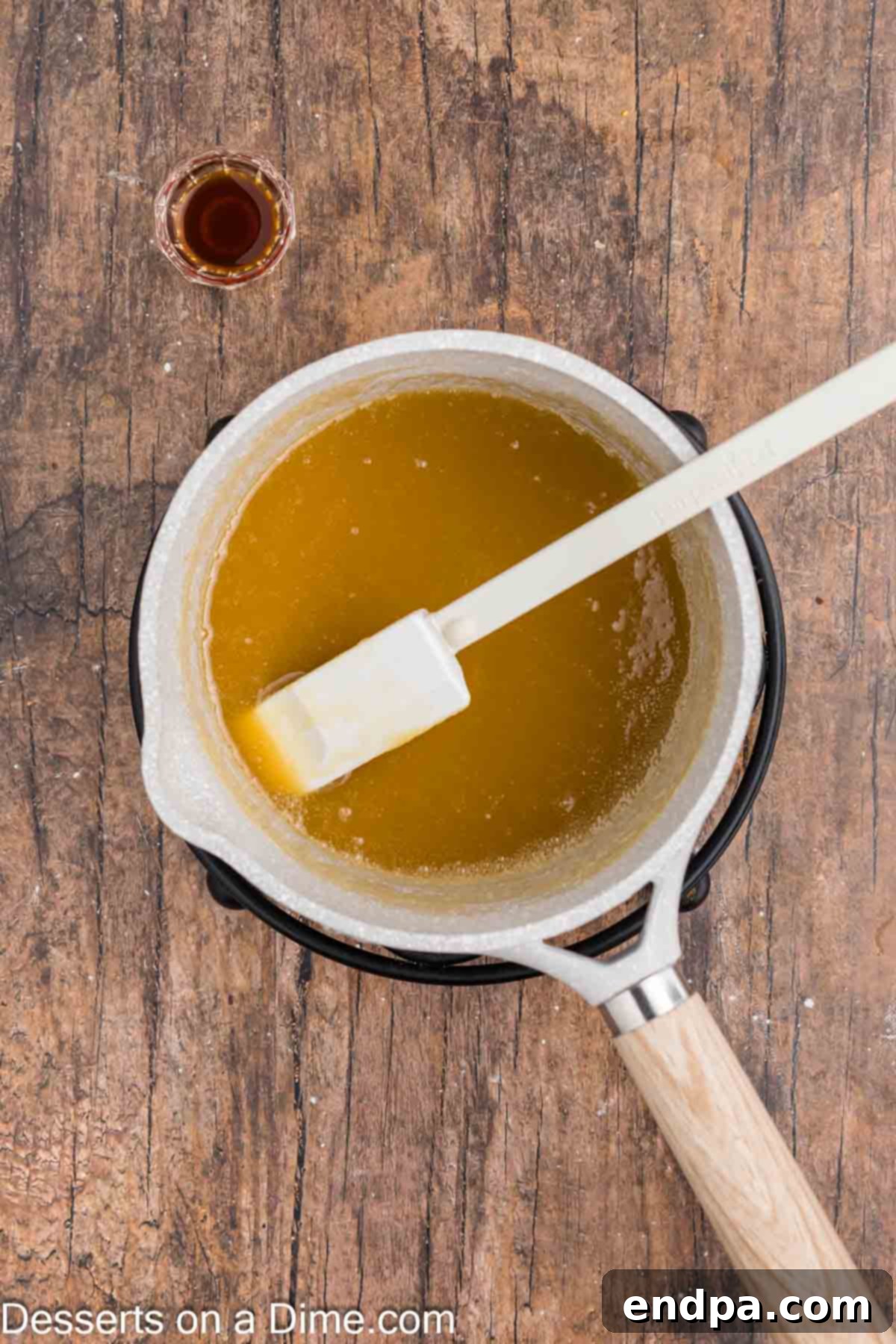 Butterscotch sauce simmering in a saucepan on the stove, beginning to thicken.