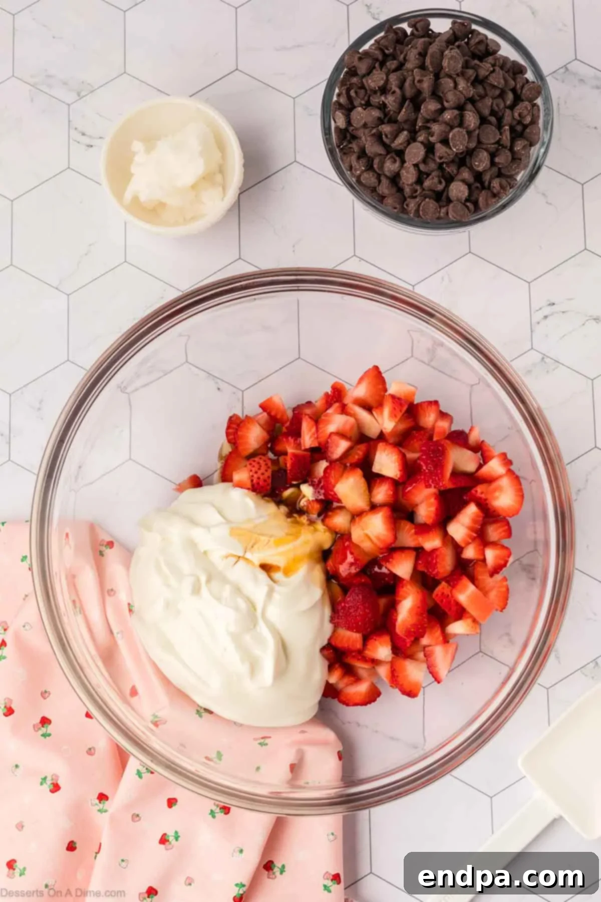 A large mixing bowl containing chopped fresh strawberries, plain Greek yogurt, honey or maple syrup, and vanilla extract.