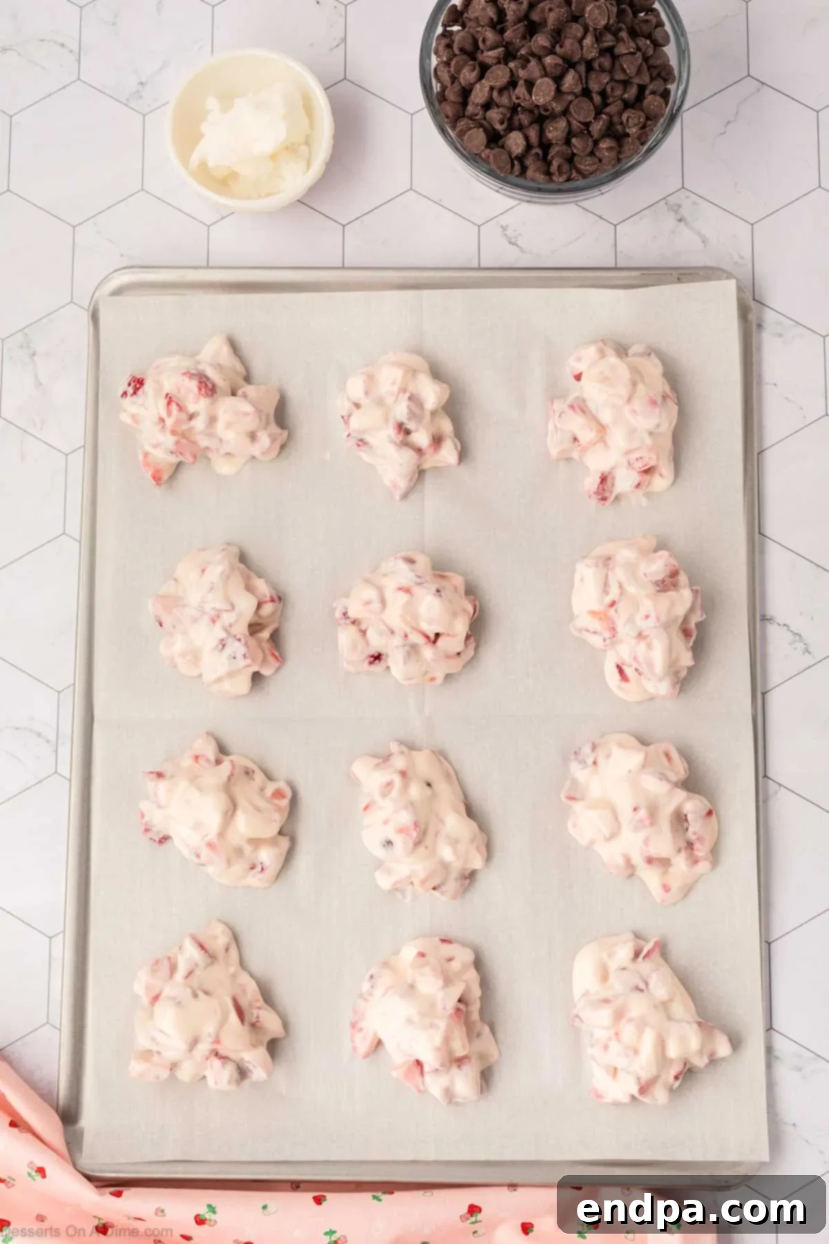 Yogurt clusters dropped onto a parchment-lined baking sheet, ready for freezing.