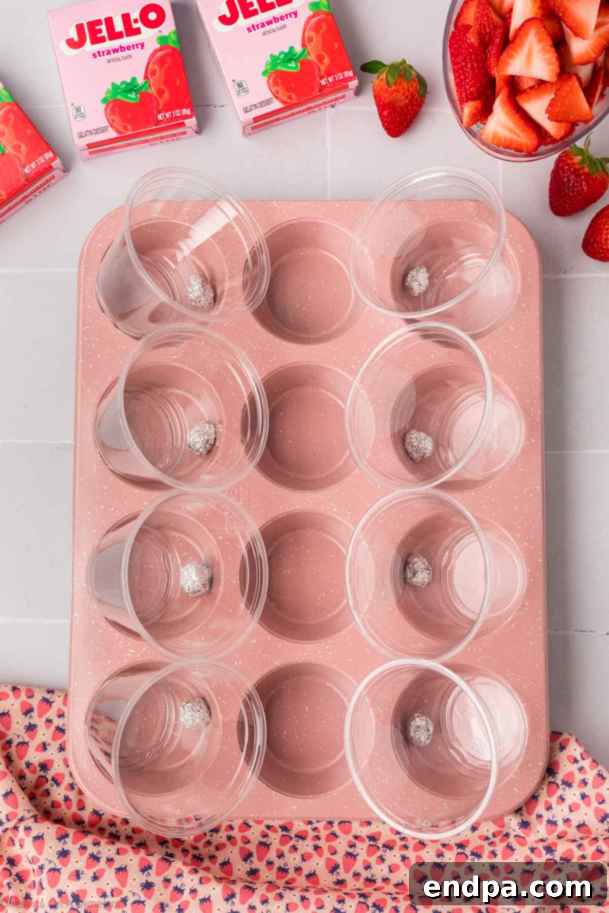 Plastic cups positioned at a slant in a muffin tin, held by aluminum foil.