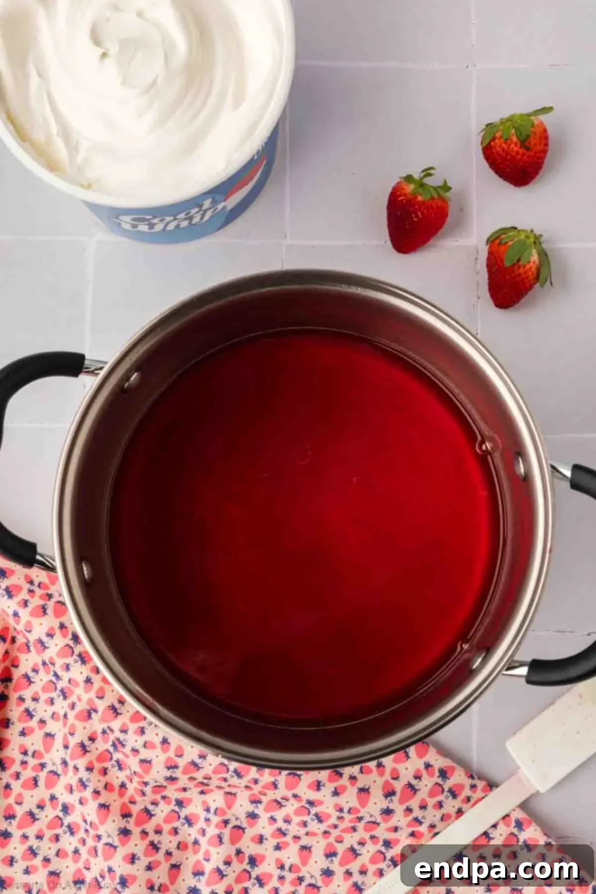 A saucepan containing dissolved strawberry Jello mixture.