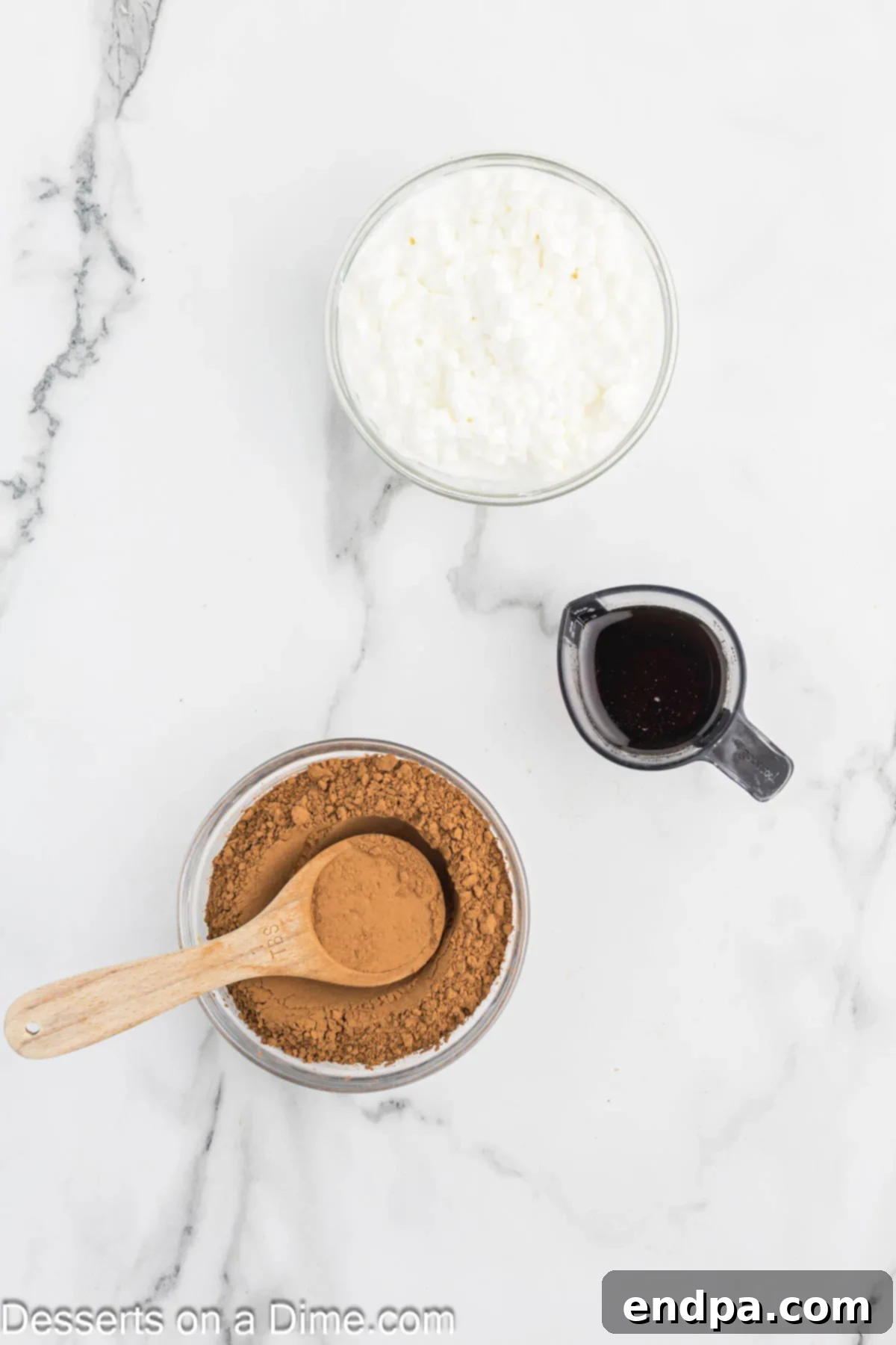 Wholesome Curd Delight 3 Cottage cheese, cocoa powder, and maple syrup laid out on a kitchen counter, the three essential ingredients for the pudding.
