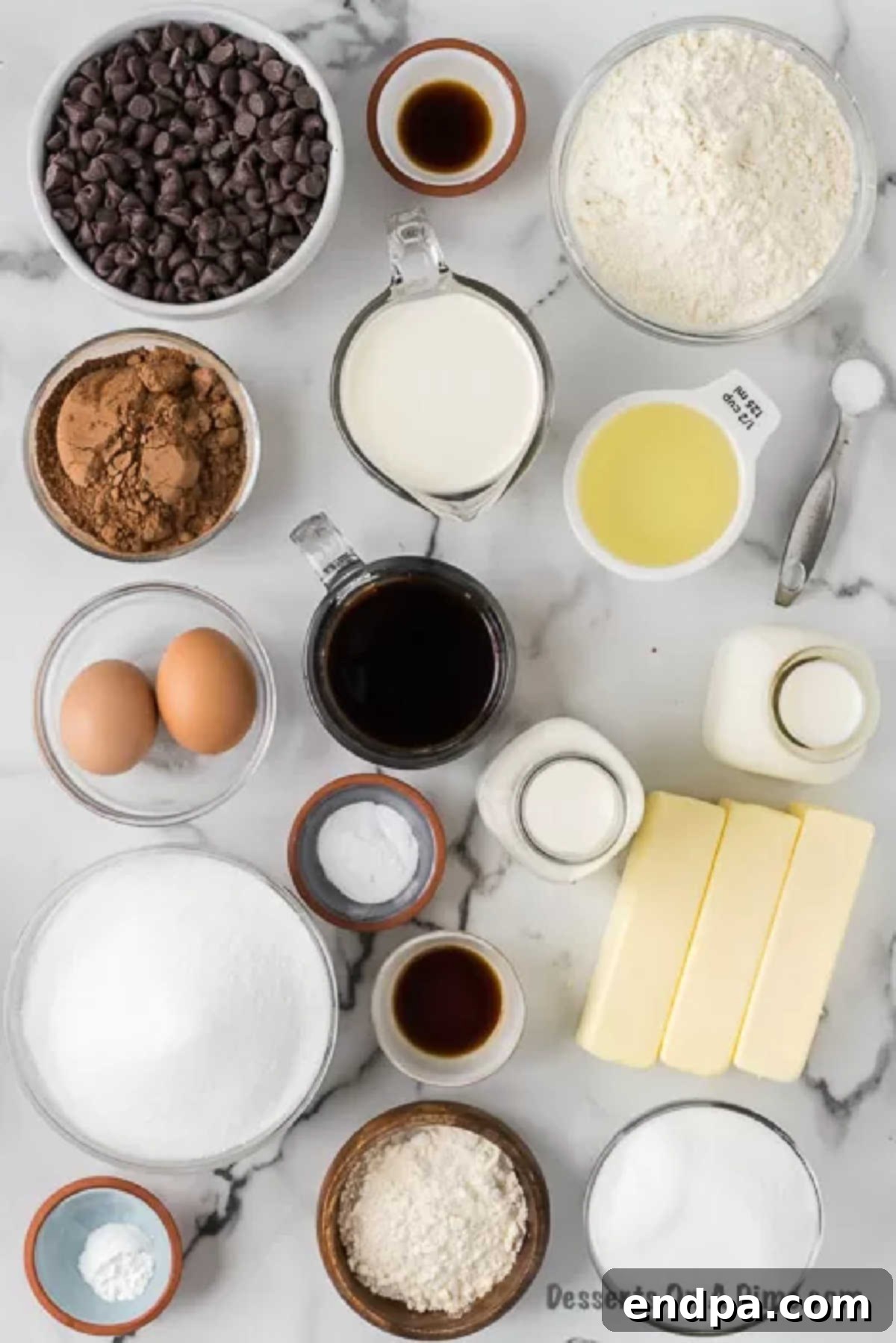 A flat lay image displaying all the ingredients for Ding Dong Cake: butter, sugar, eggs, flour, cocoa powder, baking soda, oil, vanilla, coffee, milk, chocolate chips, and heavy whipping cream.