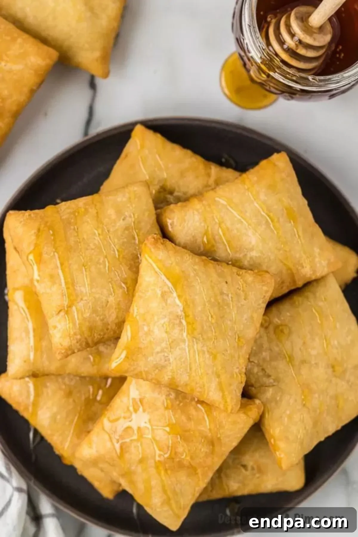 Homemade sopapillas on a plate, glistening with honey.