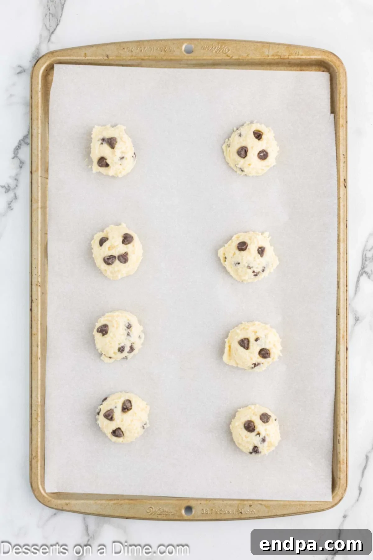Balls of cottage cheese cookie dough neatly arranged on a baking sheet lined with parchment paper, ready for baking.