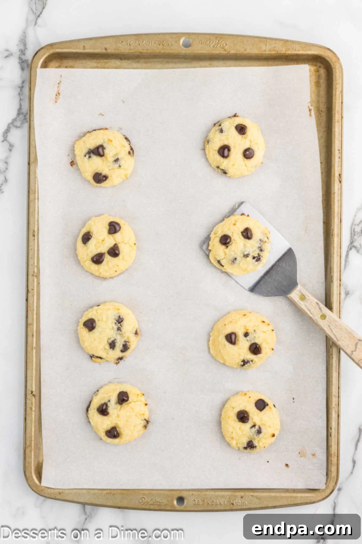 Baked cottage cheese cookies cooling on a baking sheet, with slightly golden brown edges.