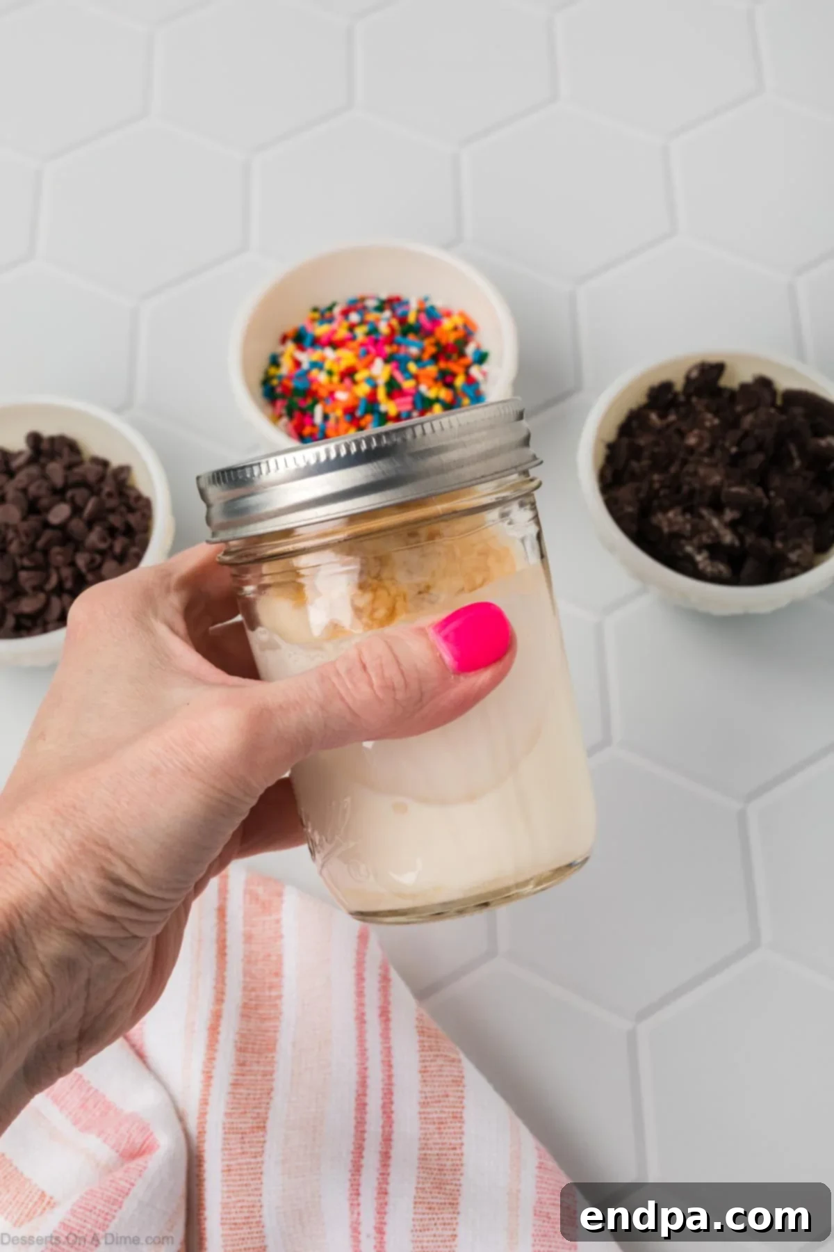 A mason jar with the lid on, actively being shaken to create the ice cream mixture, showing movement blur.