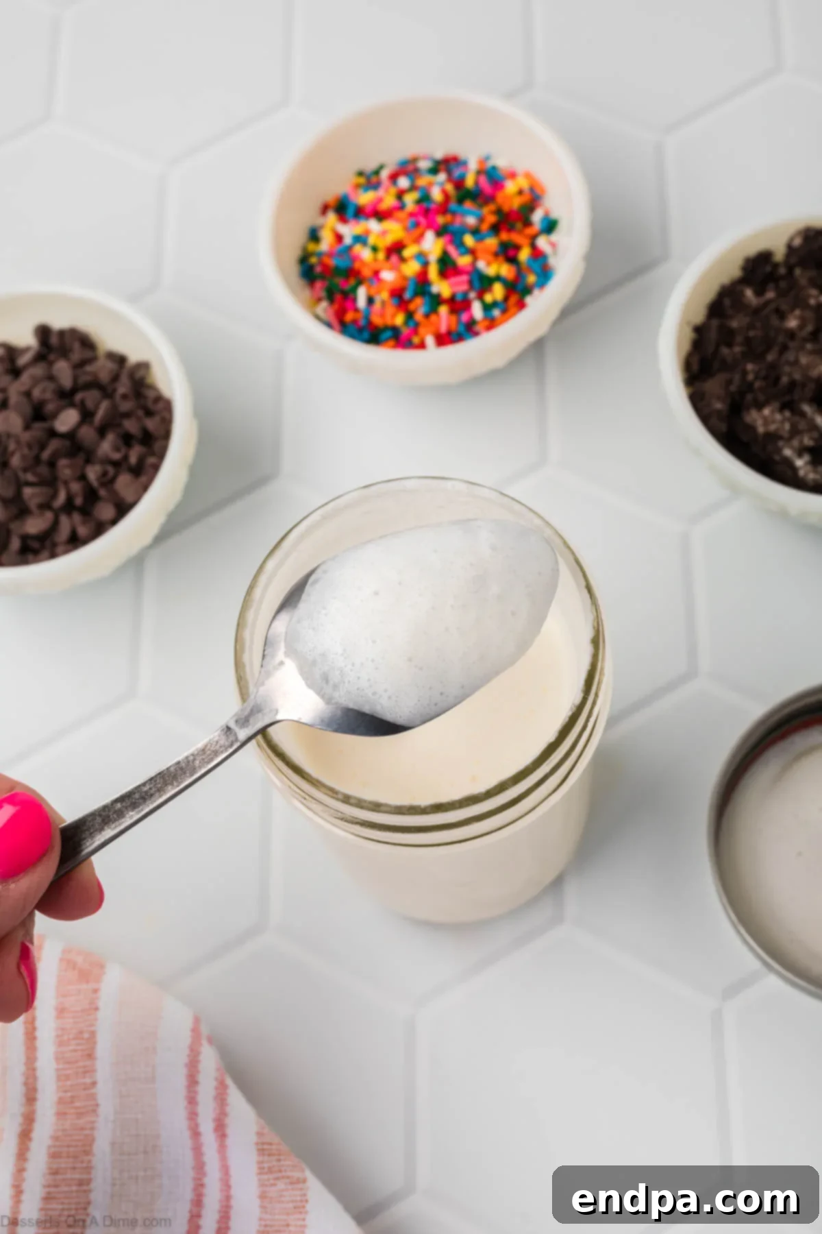 A spoon coated with the thick, creamy ice cream mixture inside the mason jar, demonstrating the desired consistency before freezing.
