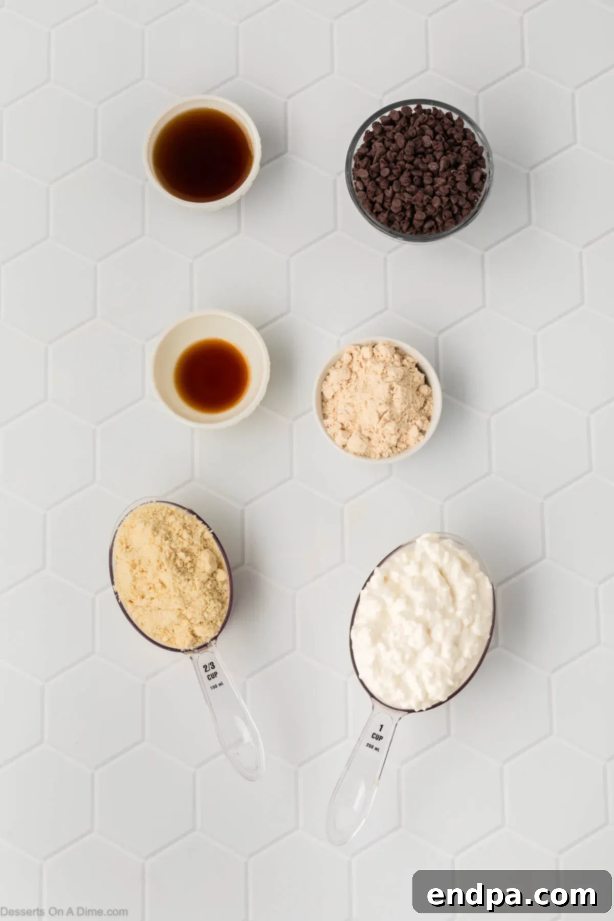 The essential ingredients for Cottage Cheese Cookie Dough laid out on a clean surface: a bowl of full-fat cottage cheese, almond flour, vanilla protein powder, pure vanilla extract, a bottle of maple syrup, and a scattering of mini chocolate chips.
