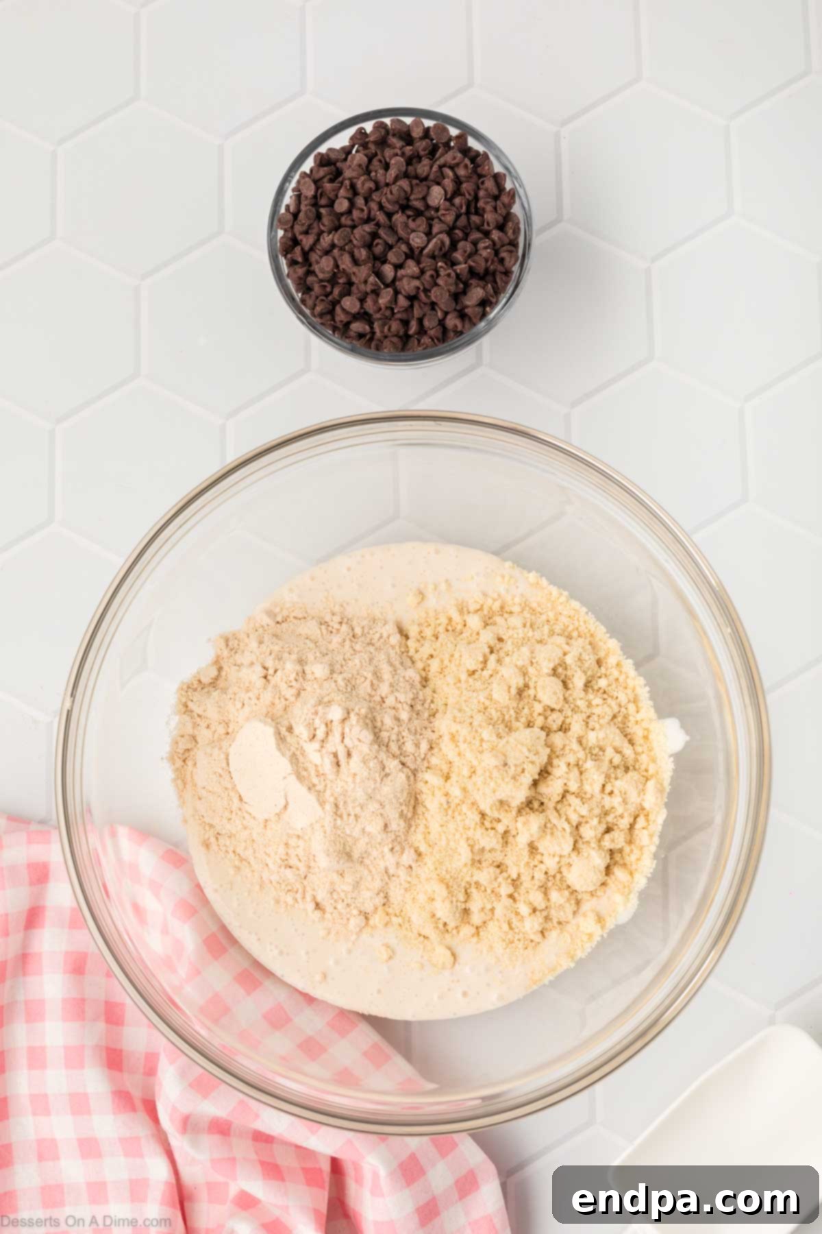 Almond flour and vanilla protein powder are being gently poured over the creamy cottage cheese mixture in the mixing bowl.