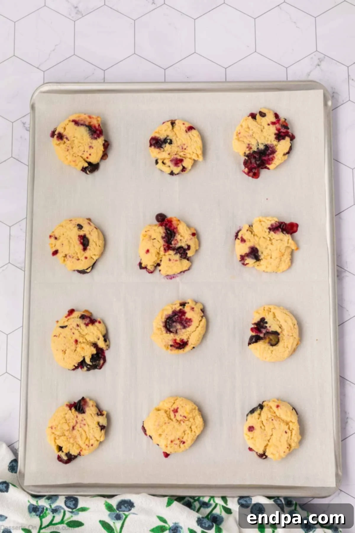 Freshly baked lemon blueberry cookies cooling on a baking sheet, showing slightly golden brown edges.
