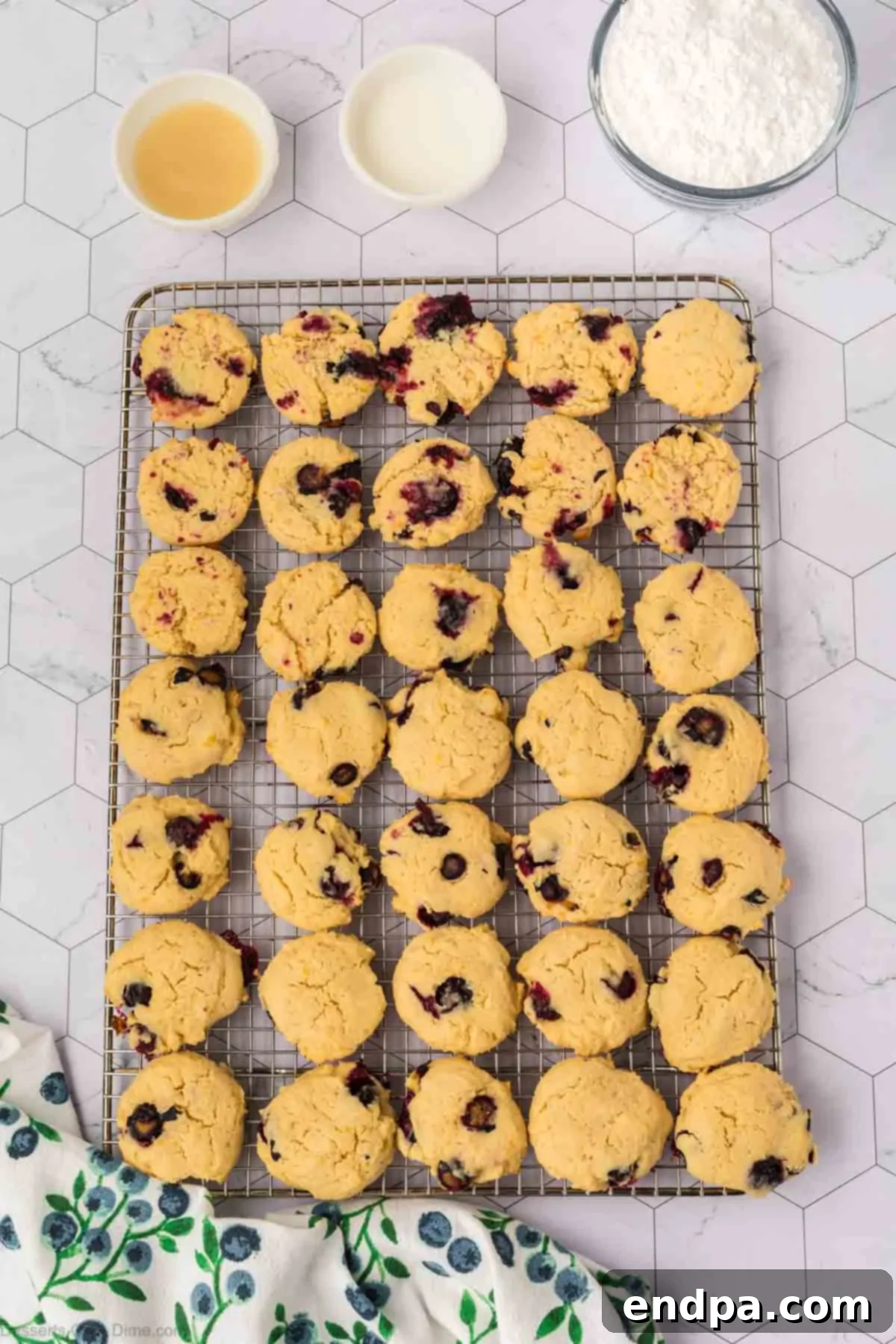 Baked lemon blueberry cookies transferring from the baking sheet to a wire rack to cool completely.