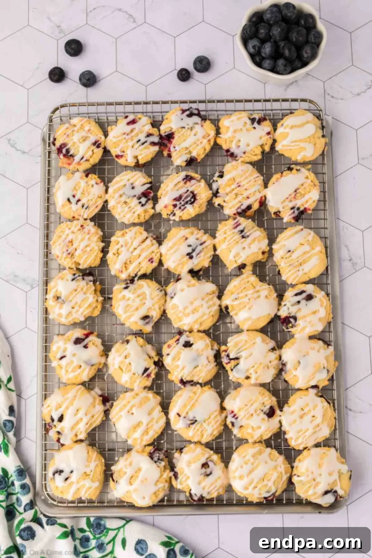 Delicate lemon glaze being drizzled artfully over cooled lemon blueberry cookies, ready for serving.