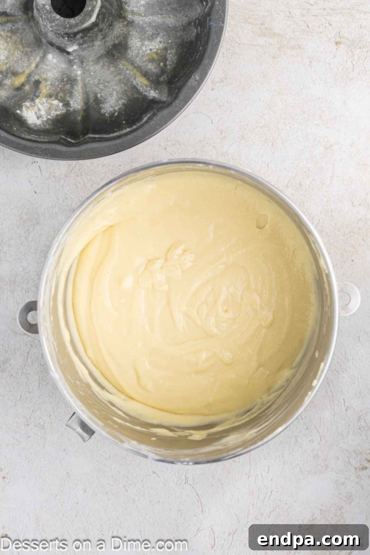 Large eggs are added one by one into the butter and sugar mixture in a stand mixer, creating a smooth, emulsified batter.