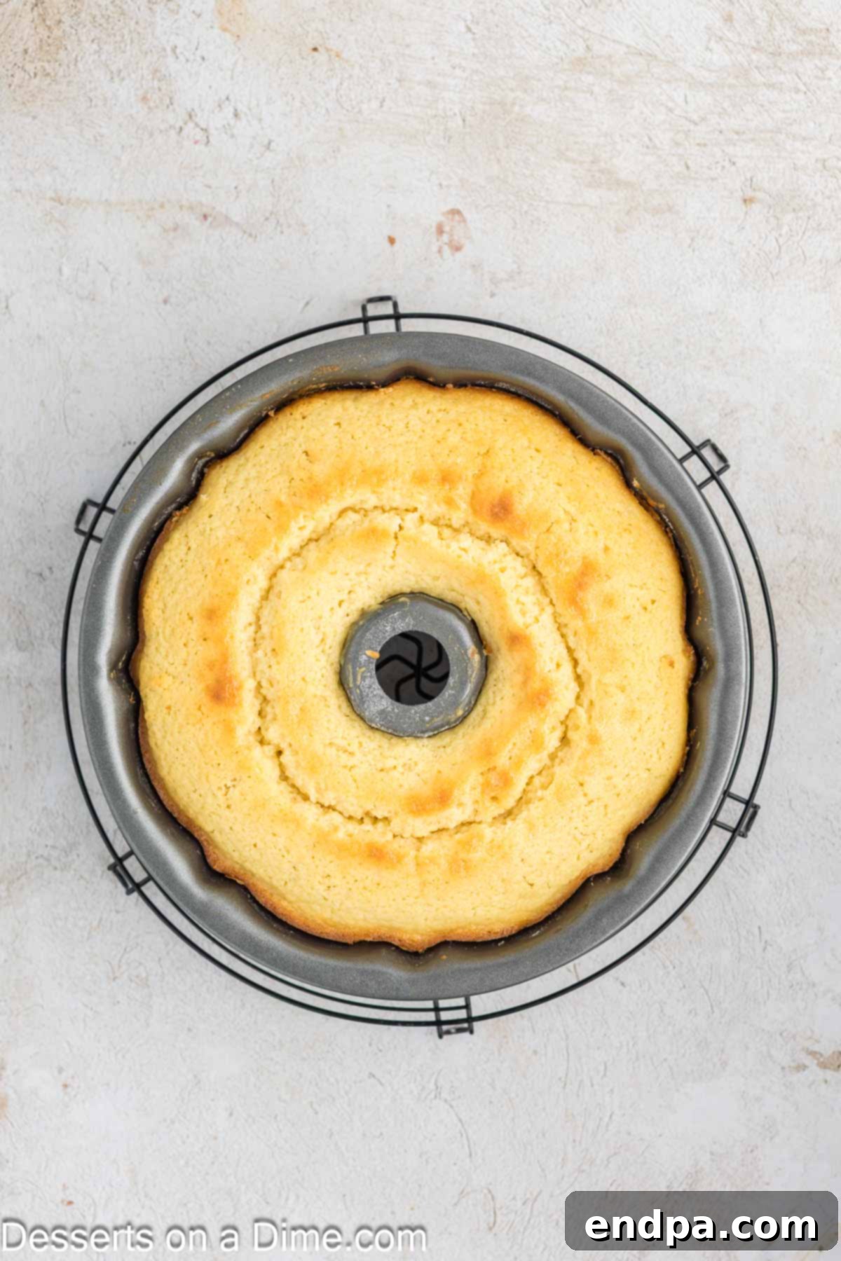 A freshly baked donut cake, golden brown and perfectly risen, cooling on a wire rack inside the bundt pan.