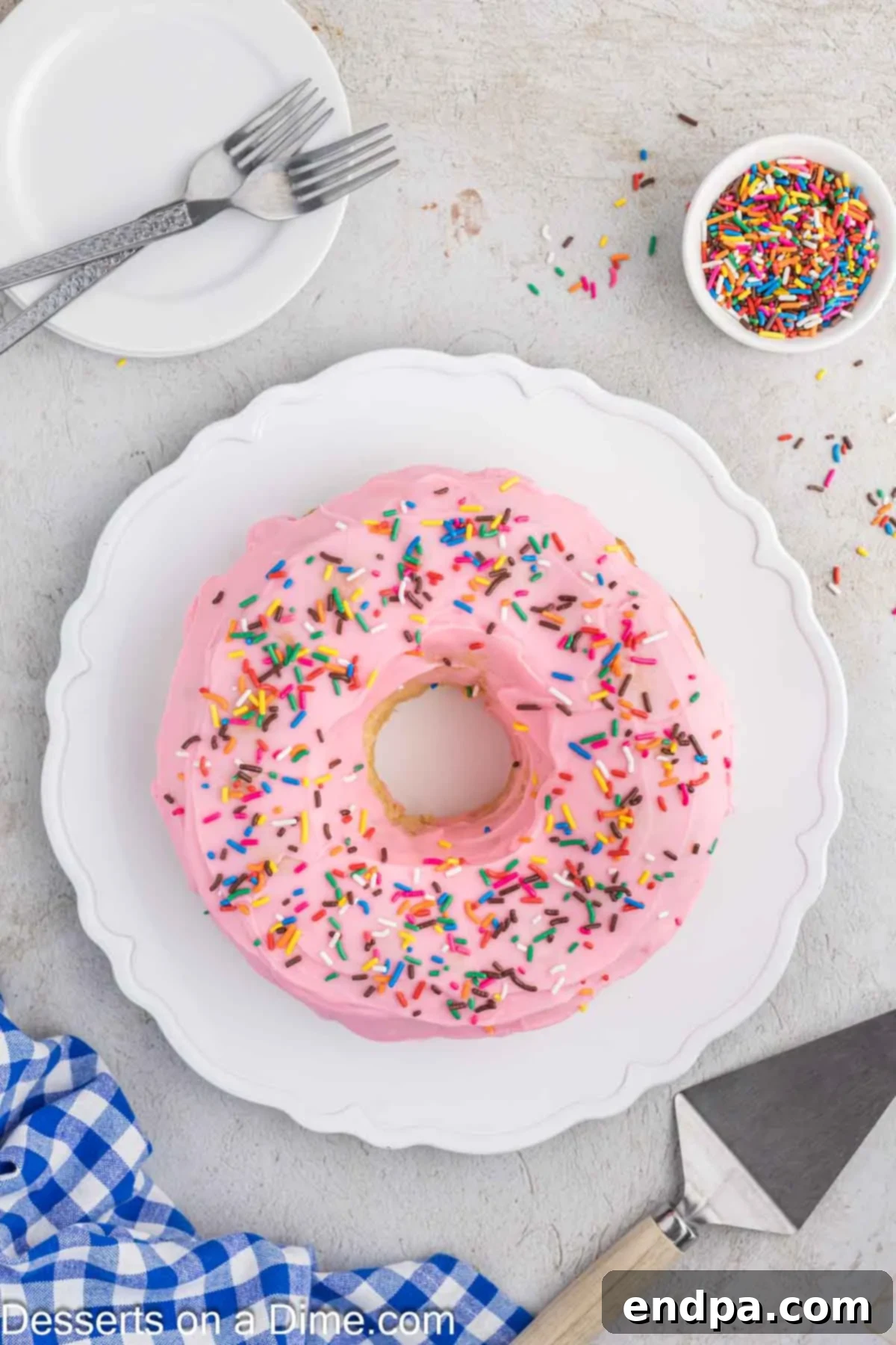 A whole Donut Cake, elegantly glazed and topped with sprinkles, resting on a decorative platter, ready to be served.