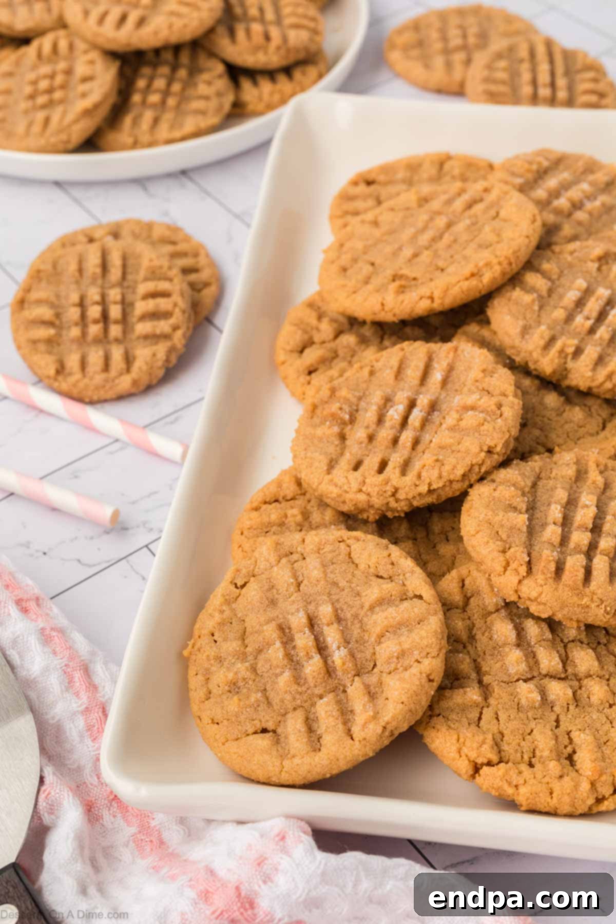 Platter of golden brown 3-ingredient peanut butter cookies with a criss-cross pattern.